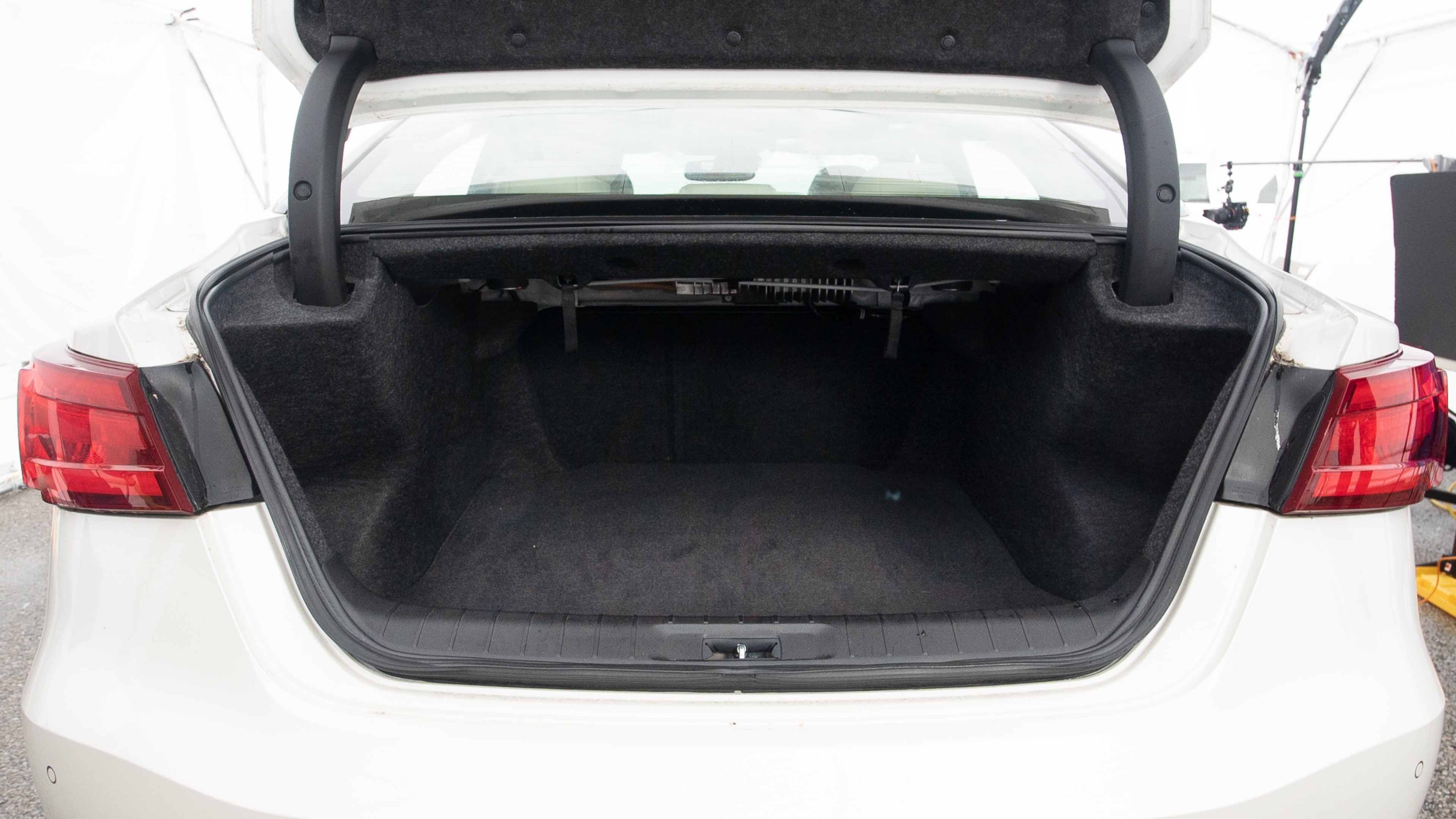 The trunk lid is open, showing full view of the trunk space. Two large and two small suitcases are placed inside.
