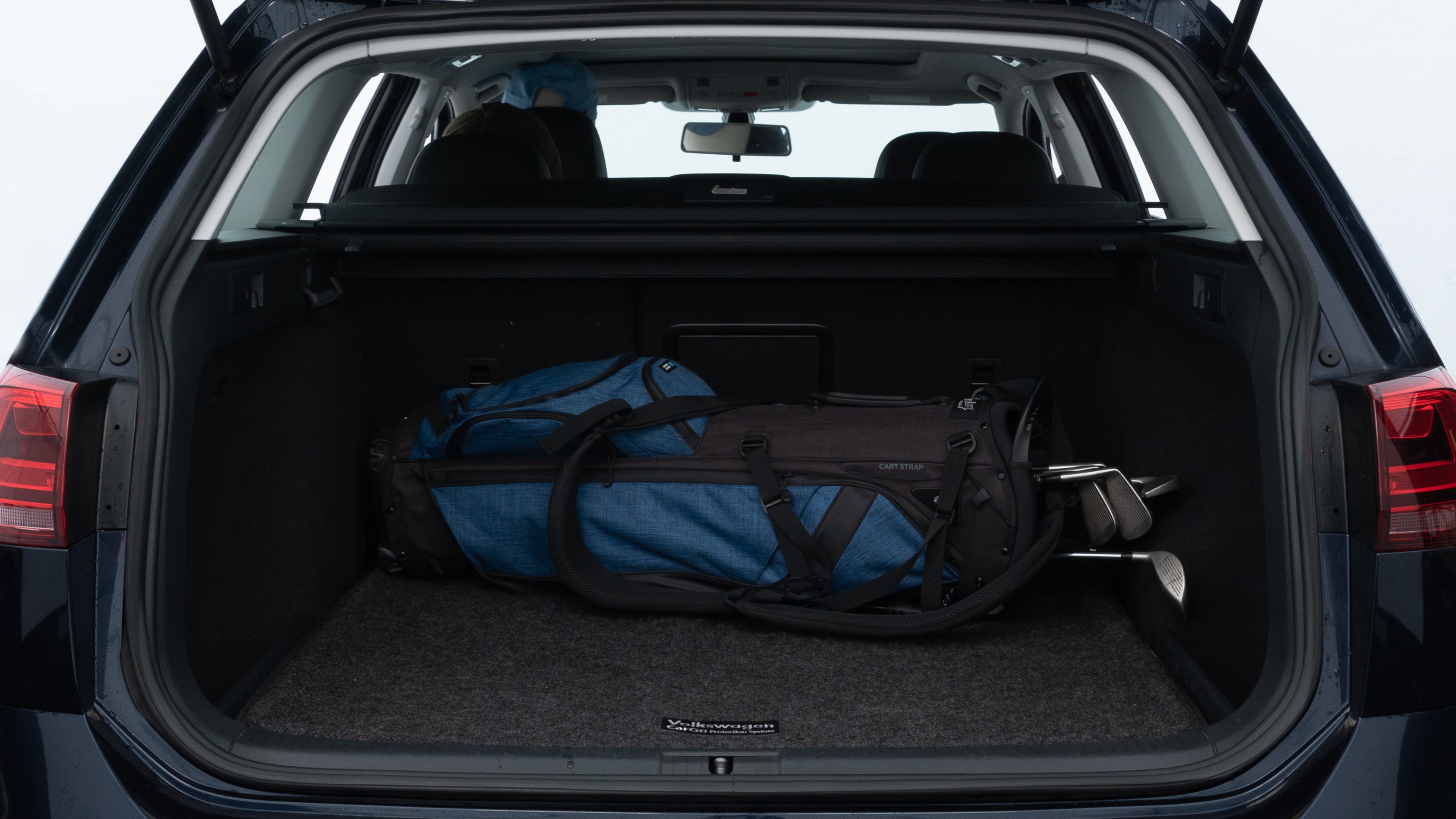 The trunk lid is open showing full view of the trunk. A baby stroller, three grocery carriers, two camping chairs in the carrying bag, and a set of golf clubs are placed inside.