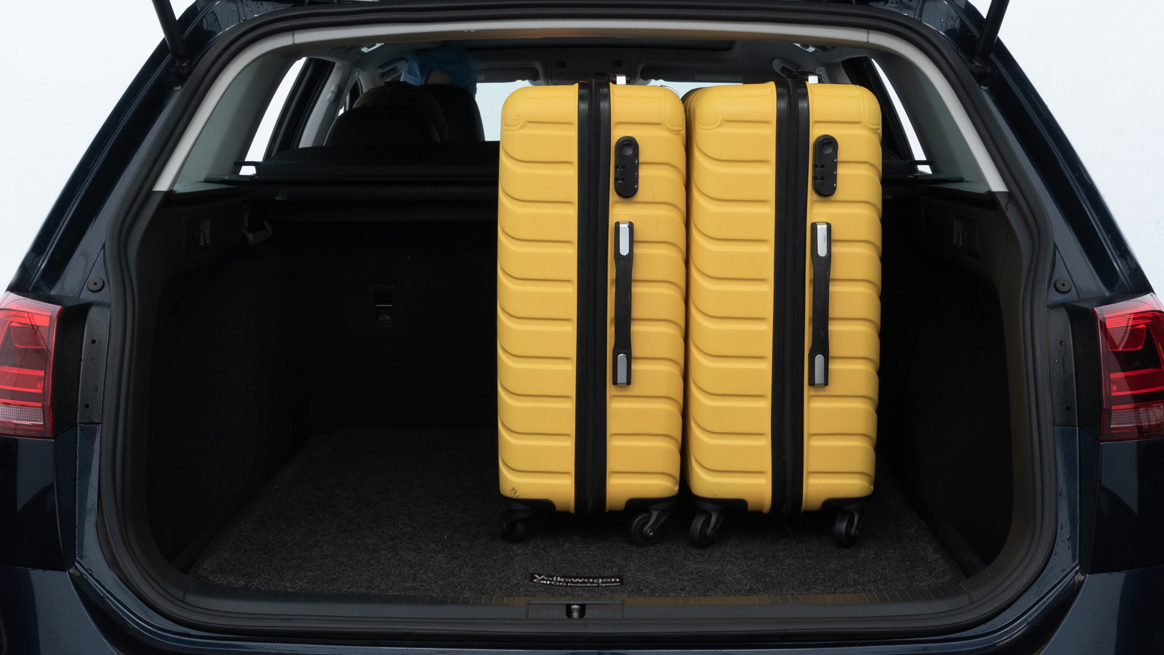 The trunk lid is open, showing full view of the trunk space. Two medium and two small suitcases are placed inside.