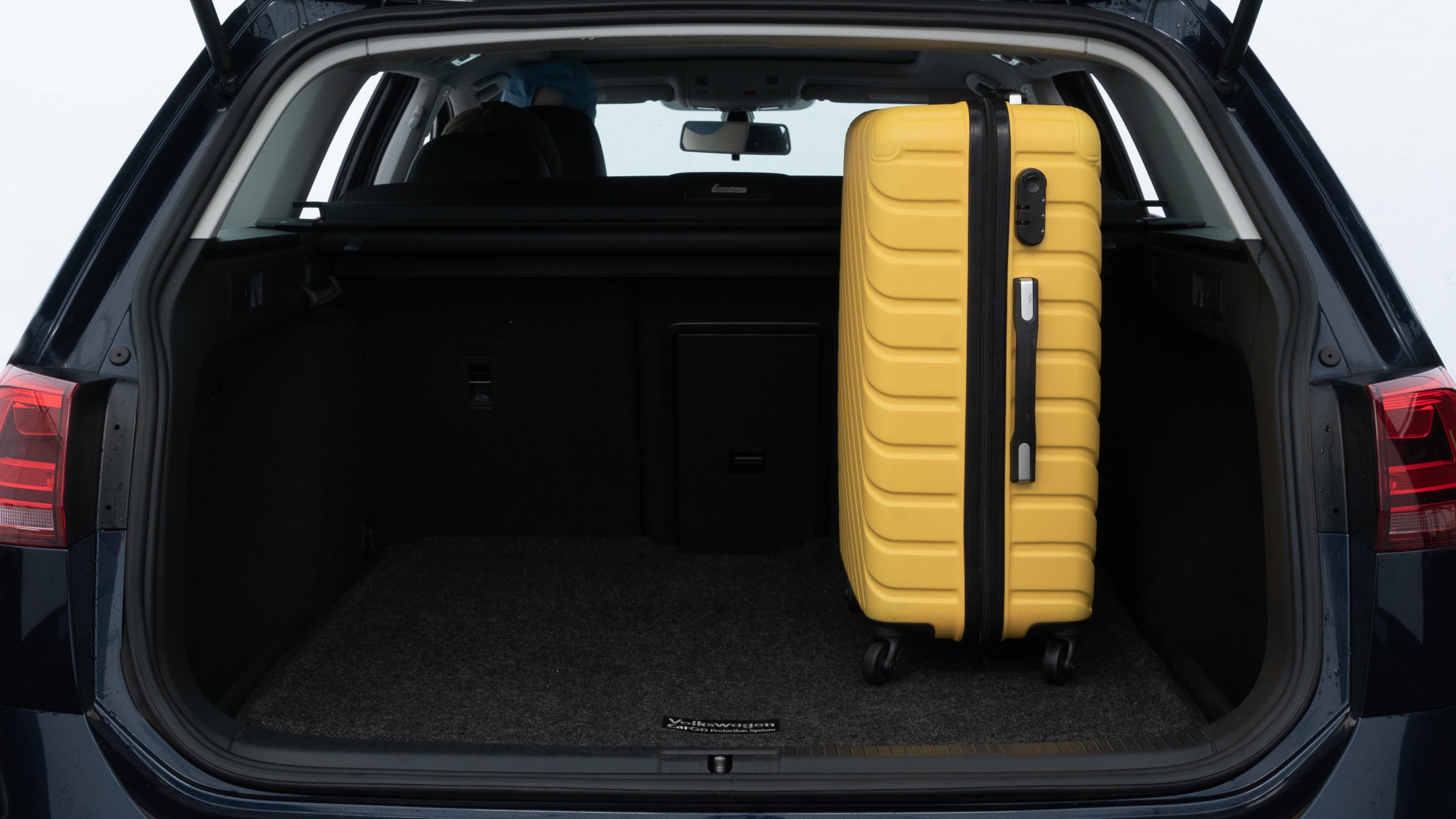 The trunk lid is open, showing full view of the trunk space. Two medium and two small suitcases are placed inside.