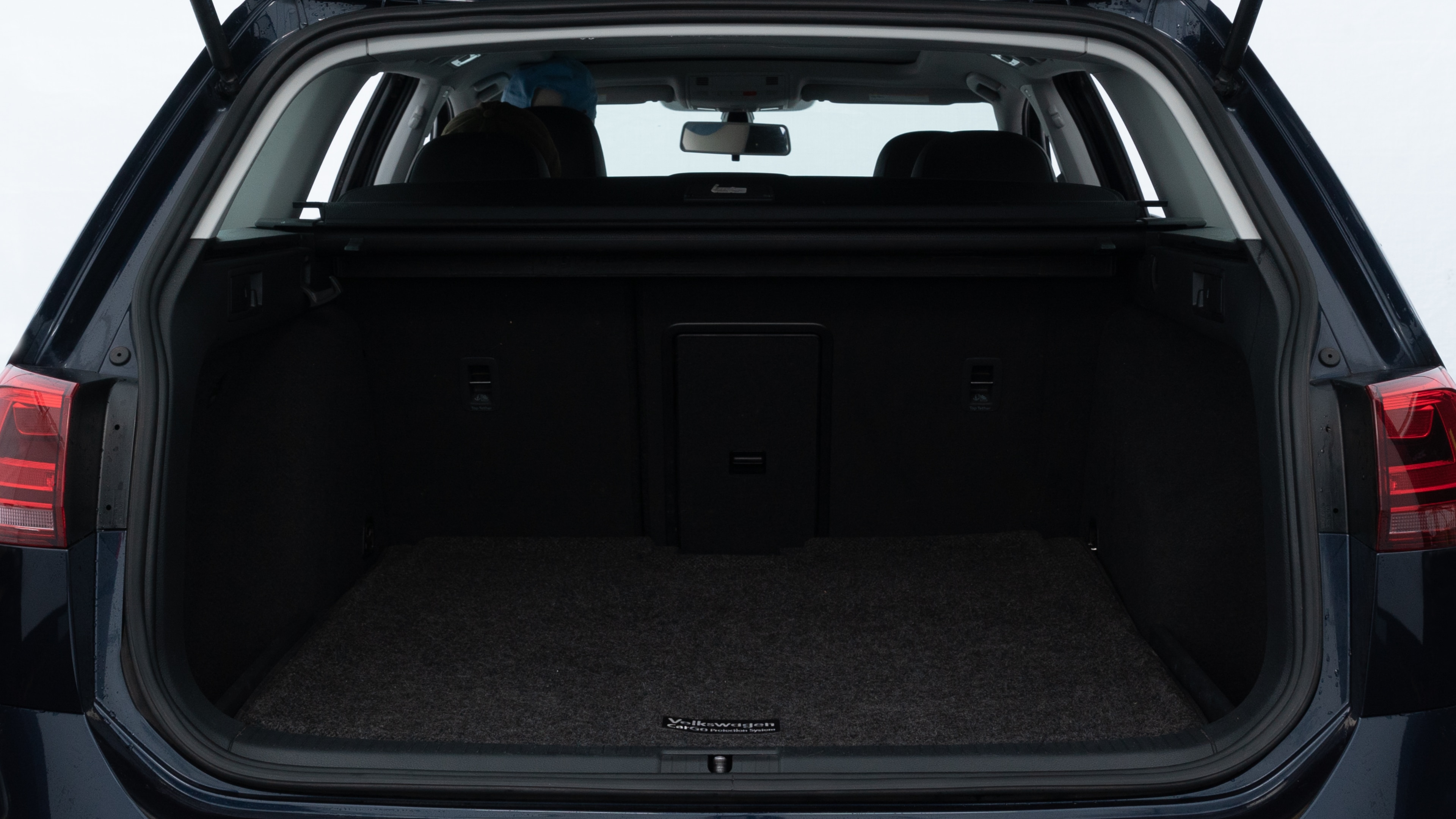 The trunk lid is open, showing full view of the trunk space. Two medium and two small suitcases are placed inside.