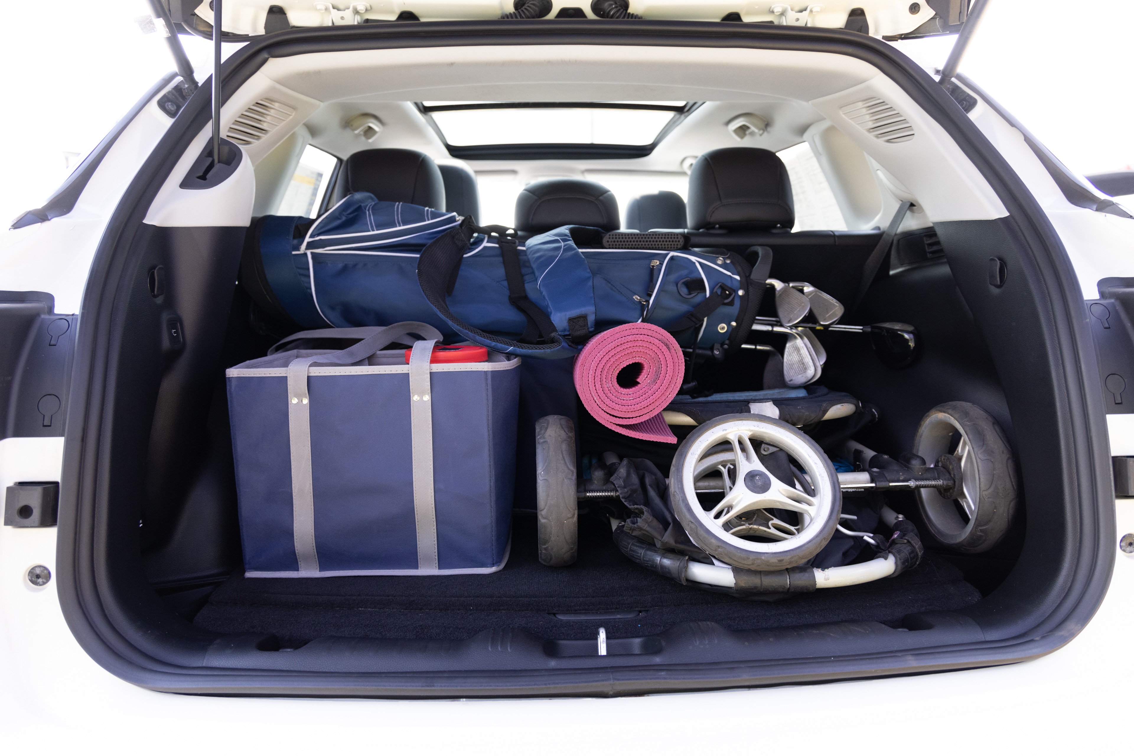 The cargo area is open giving a full view of the cargo area. A baby stroller, four grocery carriers, a yoga mat, and a set of golf clubs are placed inside.
