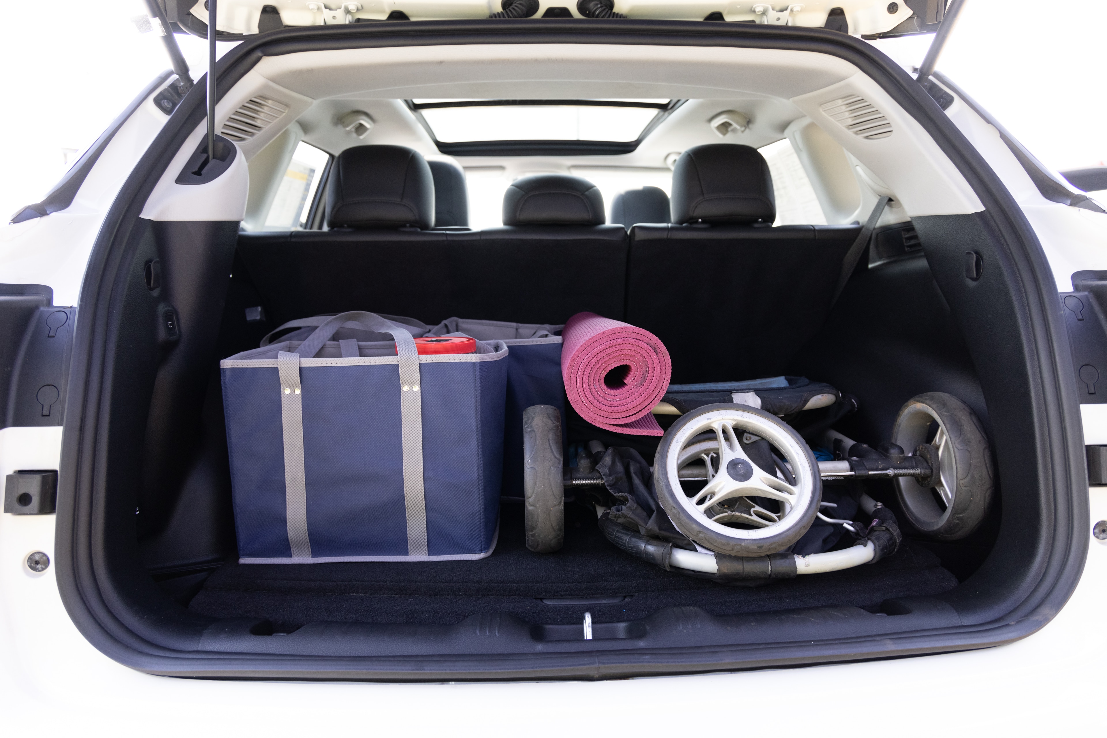 The cargo area is open giving a full view of the cargo area. A baby stroller, four grocery carriers, a yoga mat, and a set of golf clubs are placed inside.