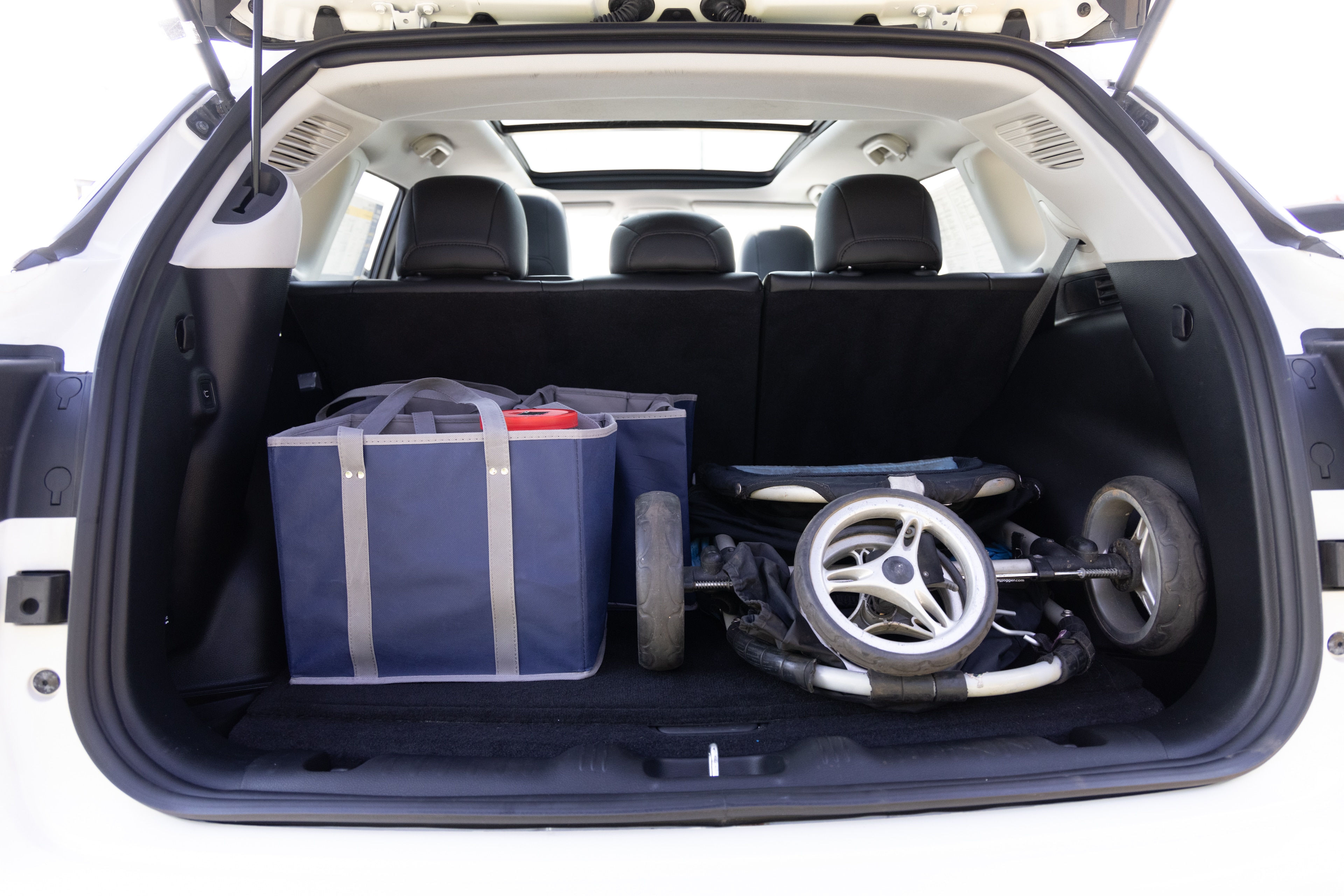 The cargo area is open giving a full view of the cargo area. A baby stroller, four grocery carriers, a yoga mat, and a set of golf clubs are placed inside.