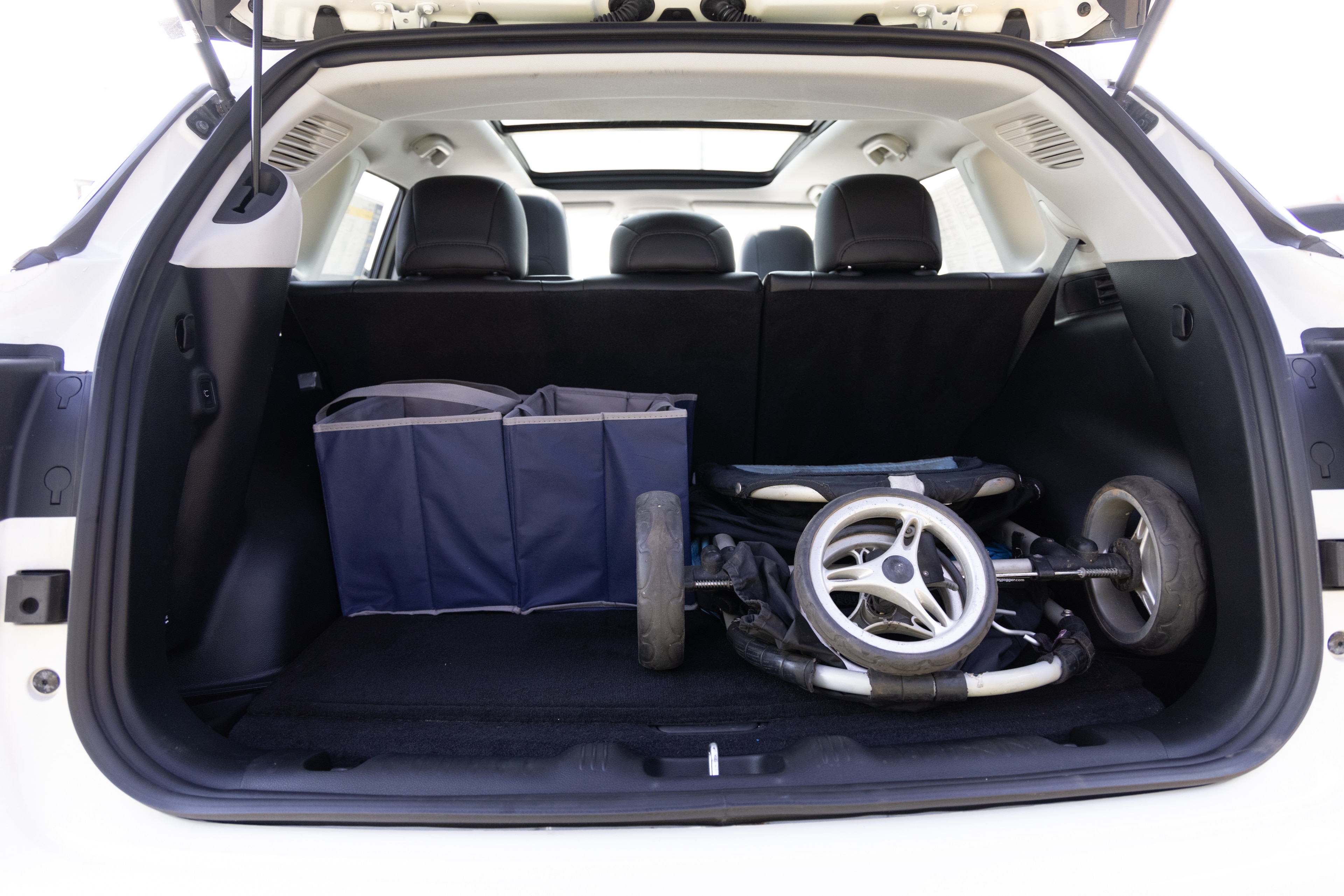 The cargo area is open giving a full view of the cargo area. A baby stroller, four grocery carriers, a yoga mat, and a set of golf clubs are placed inside.