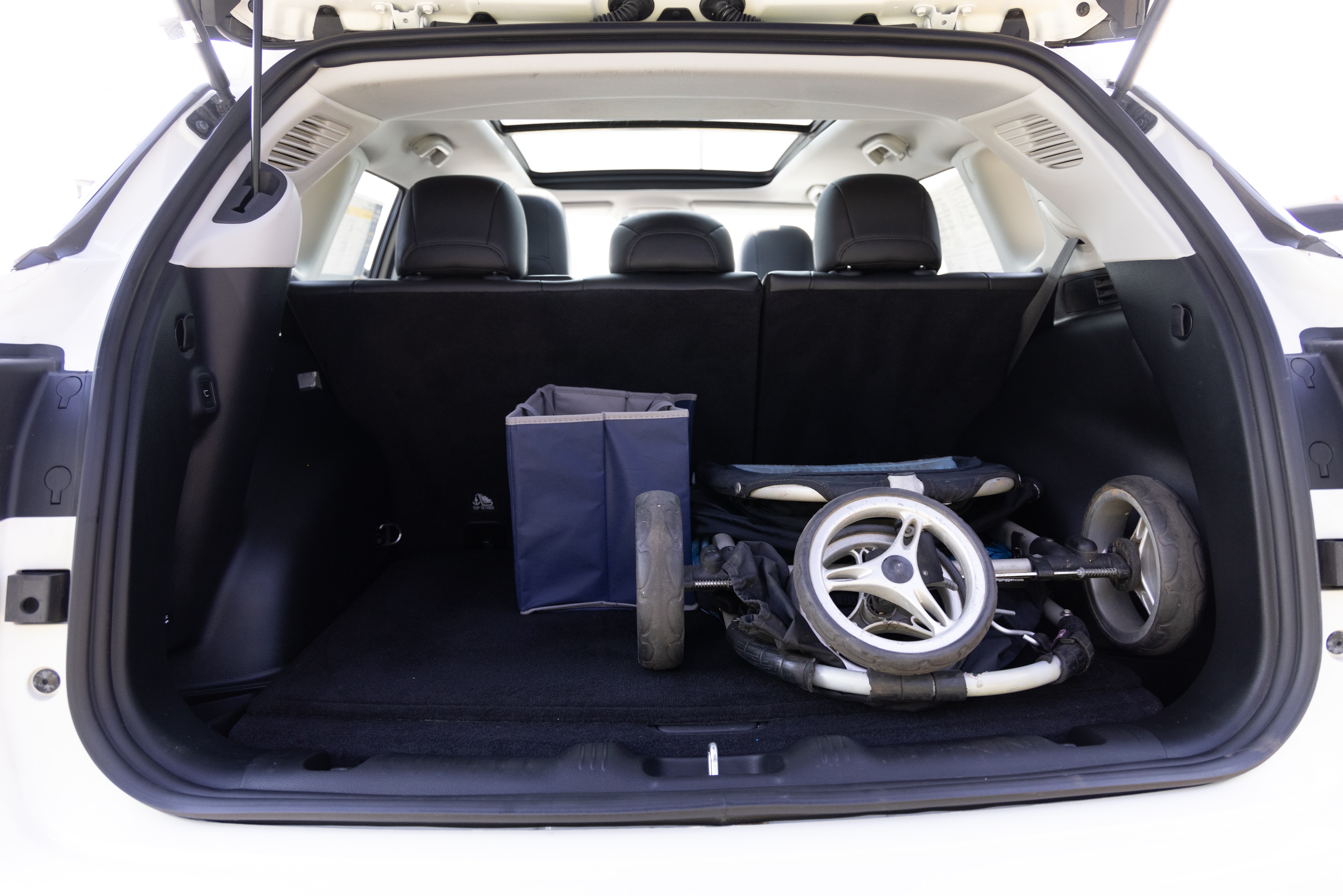 The cargo area is open giving a full view of the cargo area. A baby stroller, four grocery carriers, a yoga mat, and a set of golf clubs are placed inside.