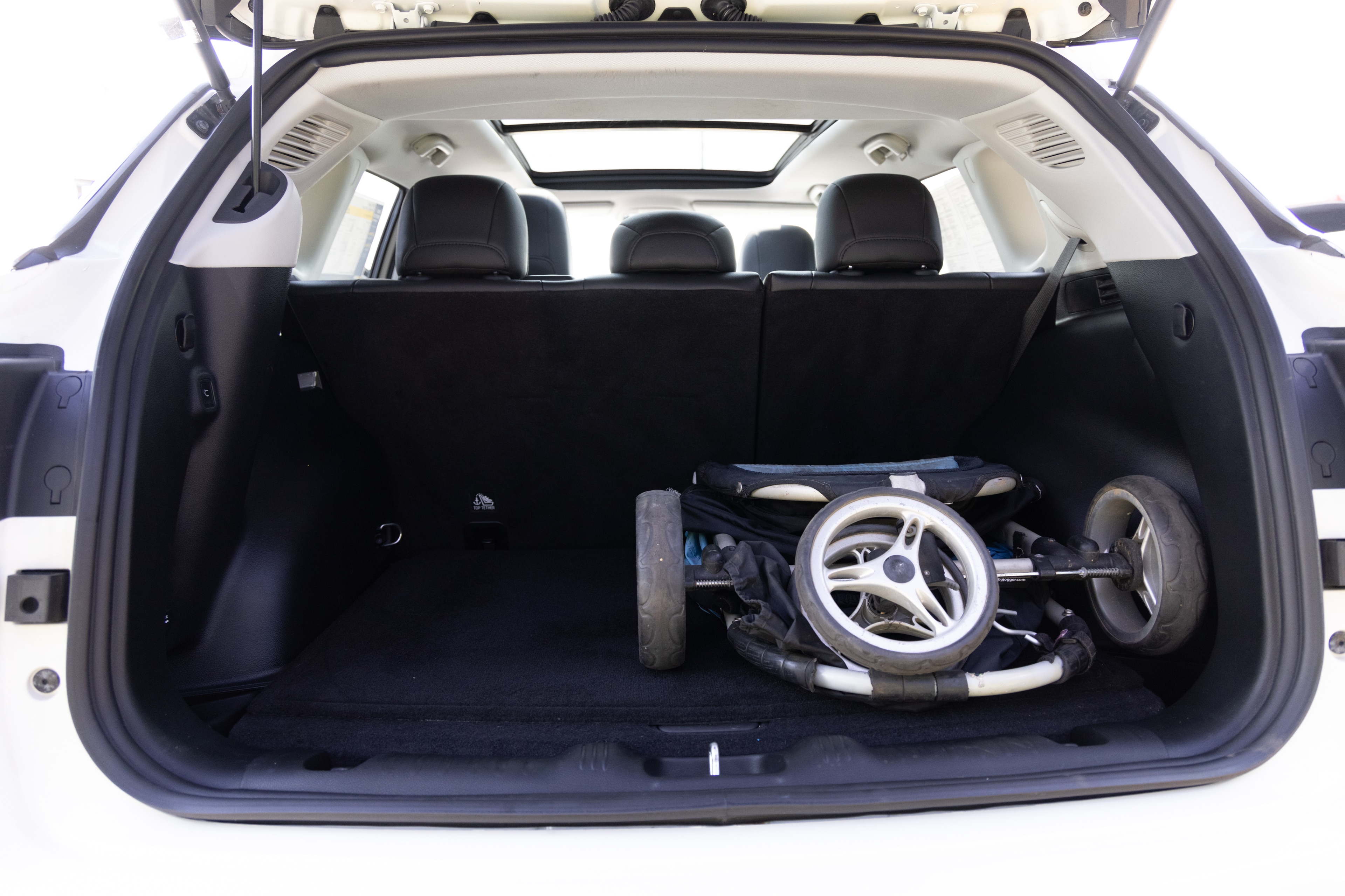 The cargo area is open giving a full view of the cargo area. A baby stroller, four grocery carriers, a yoga mat, and a set of golf clubs are placed inside.