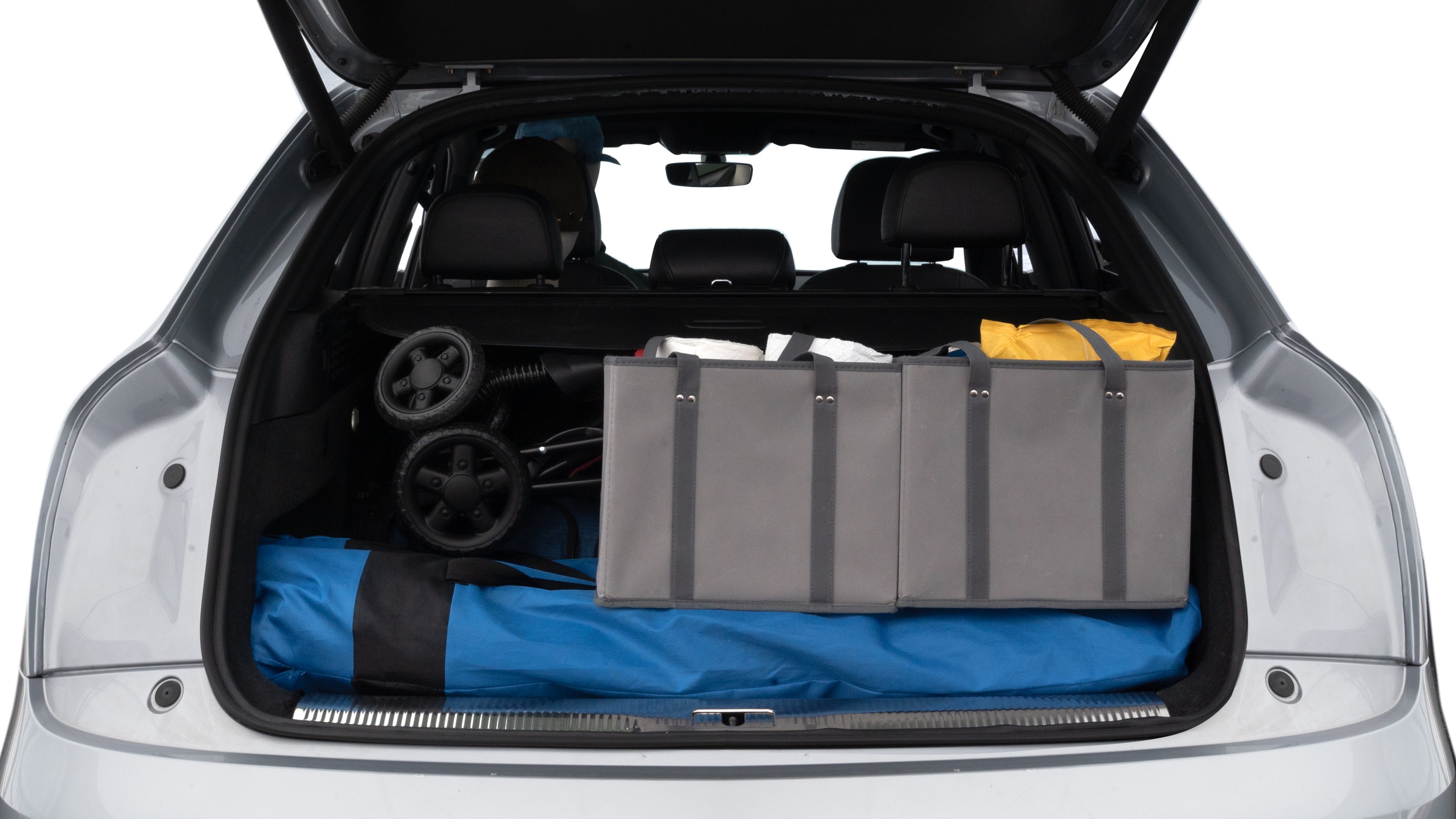The trunk lid is open showing full view of the trunk. A baby stroller, three grocery carriers, two camping chairs in the carrying bag, and a set of golf clubs are placed inside.