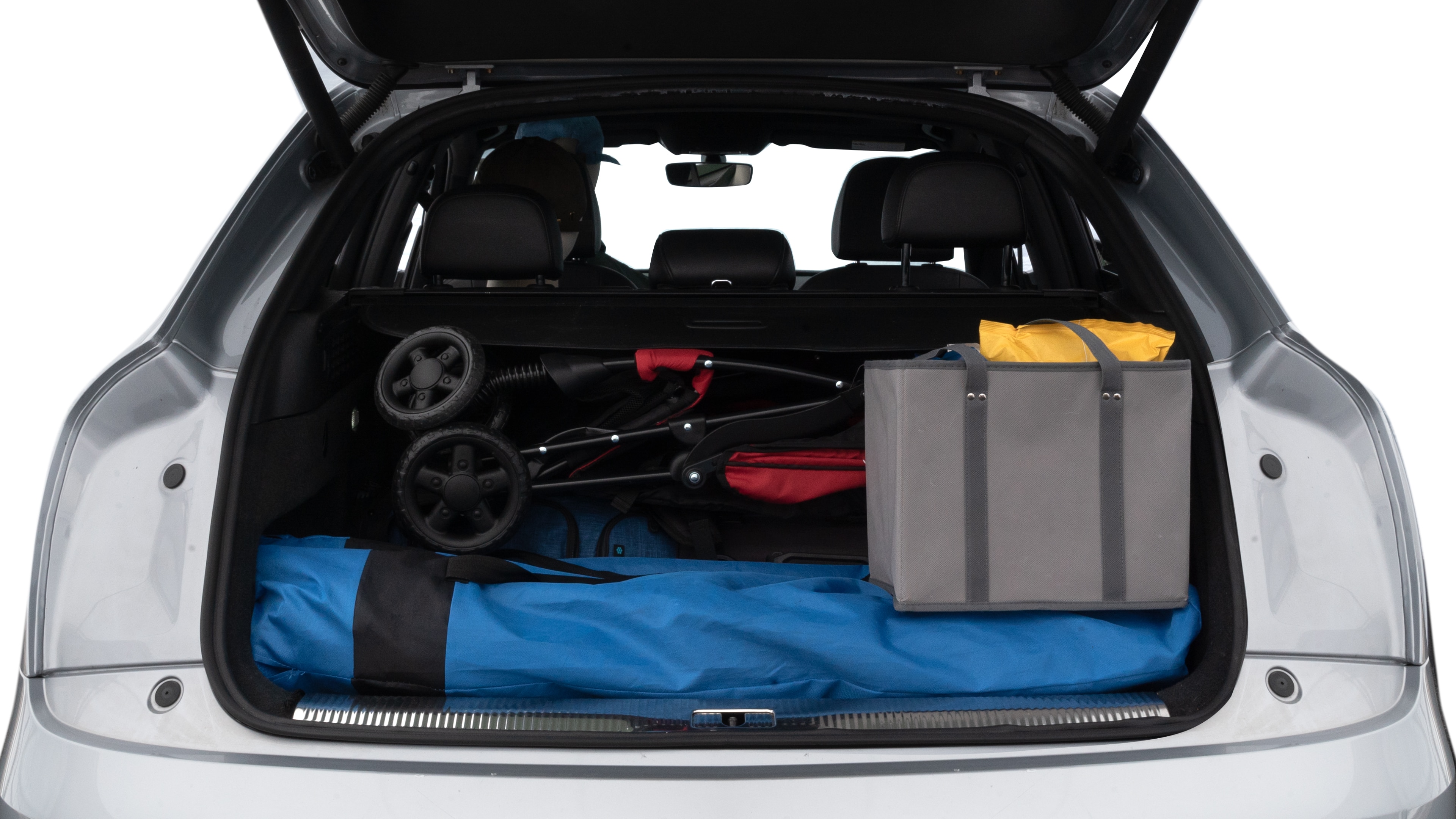 The trunk lid is open showing full view of the trunk. A baby stroller, three grocery carriers, two camping chairs in the carrying bag, and a set of golf clubs are placed inside.