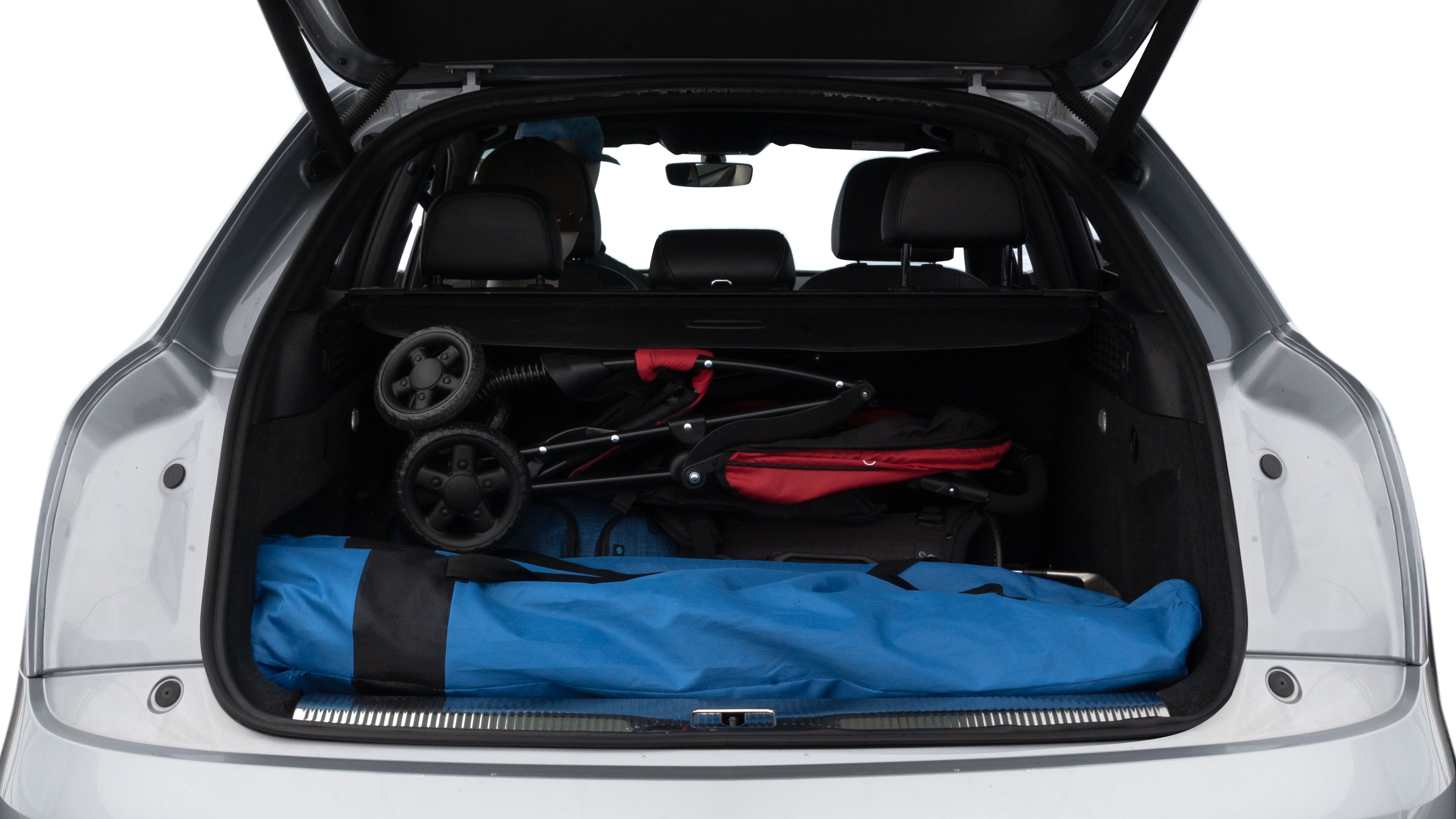 The trunk lid is open showing full view of the trunk. A baby stroller, three grocery carriers, two camping chairs in the carrying bag, and a set of golf clubs are placed inside.