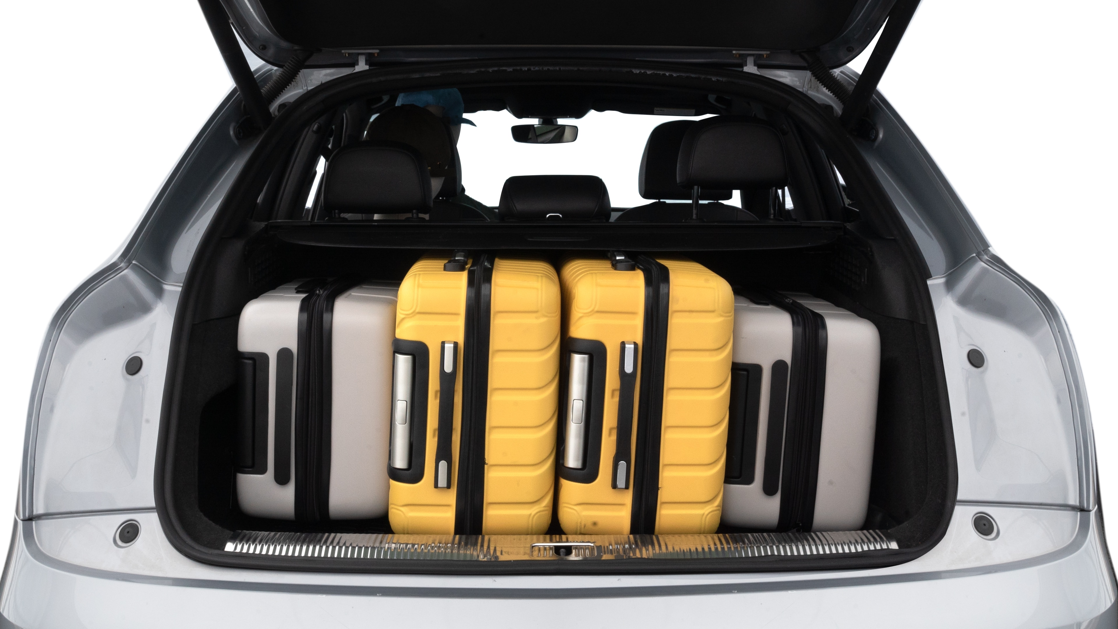 The trunk lid is open, showing full view of the trunk space. Two medium and two small suitcases are placed inside.