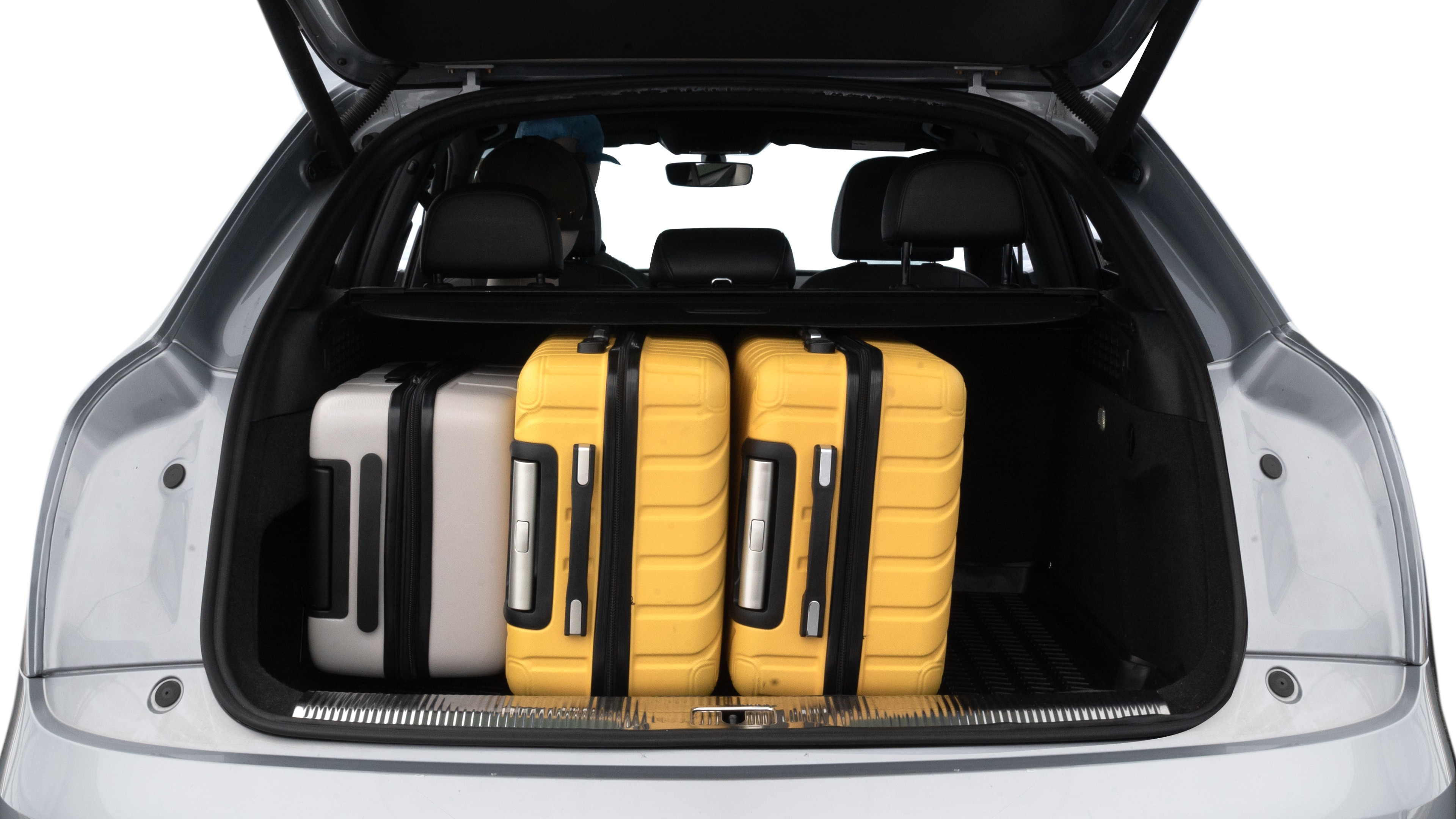 The trunk lid is open, showing full view of the trunk space. Two medium and two small suitcases are placed inside.