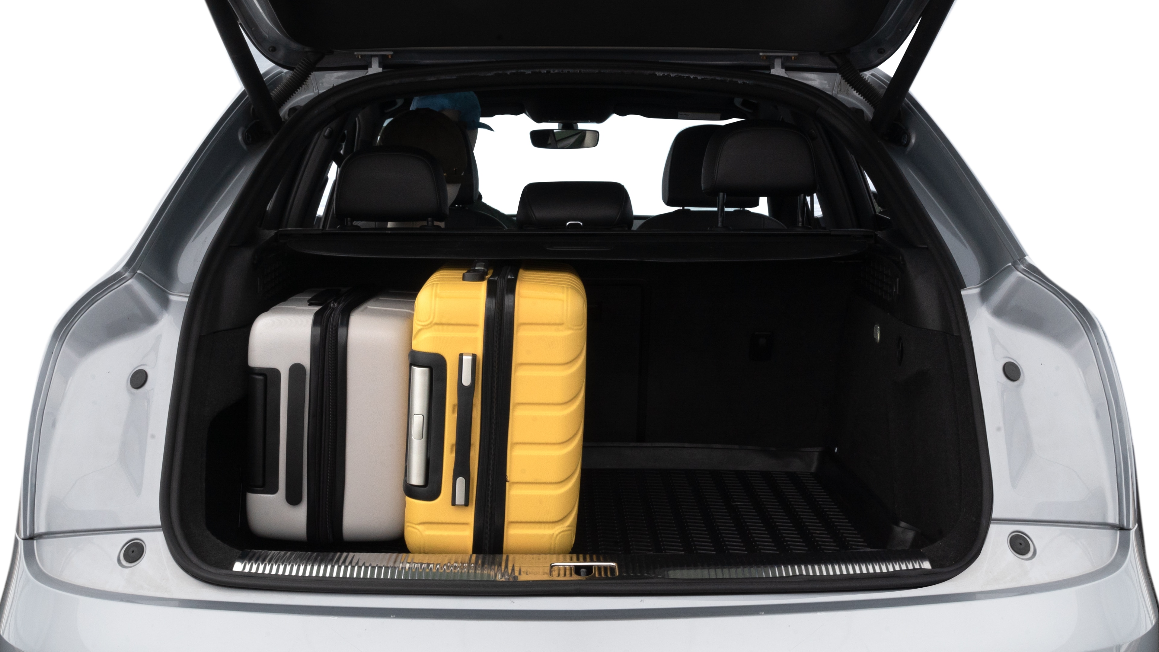 The trunk lid is open, showing full view of the trunk space. Two medium and two small suitcases are placed inside.