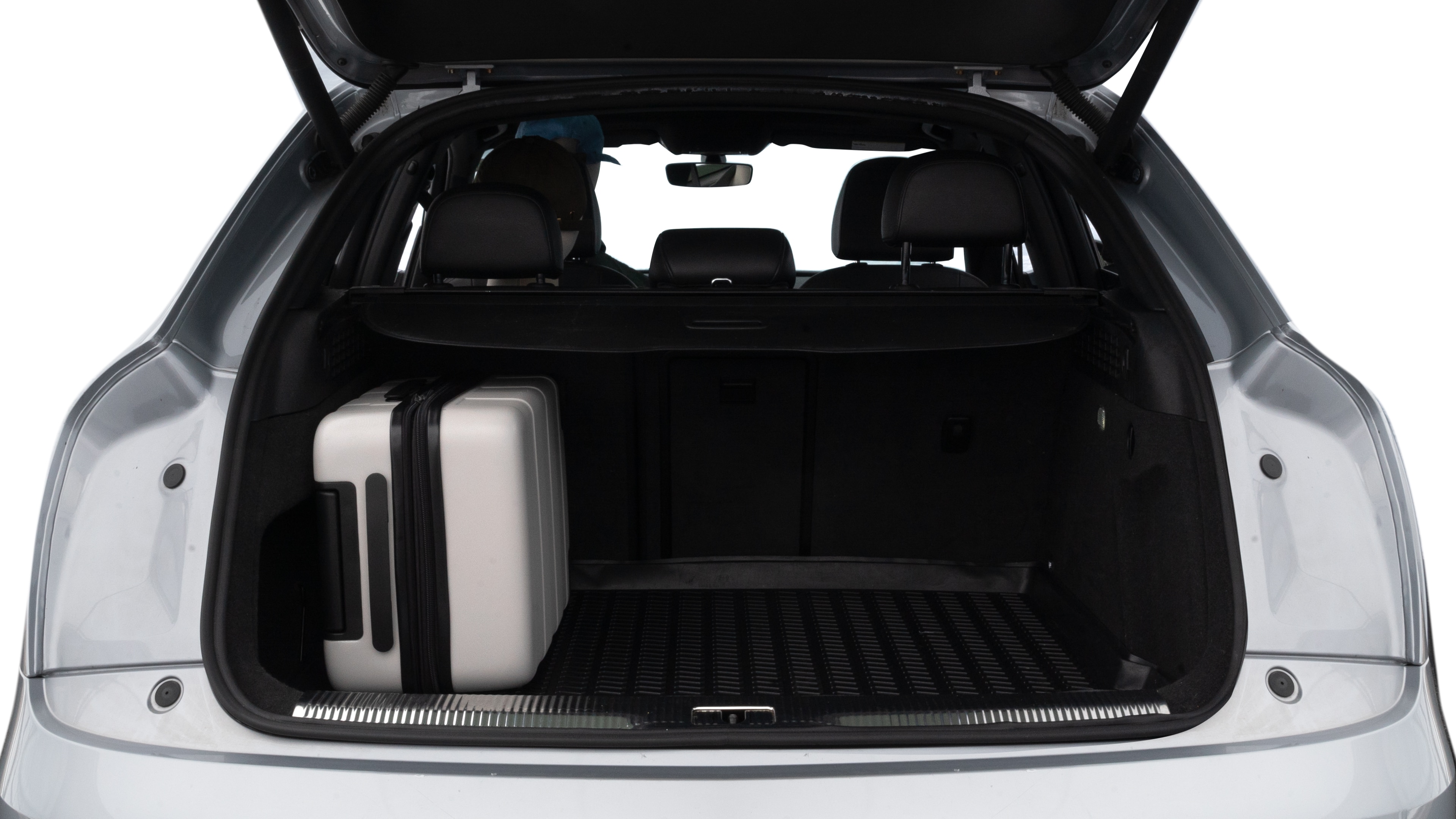 The trunk lid is open, showing full view of the trunk space. Two medium and two small suitcases are placed inside.
