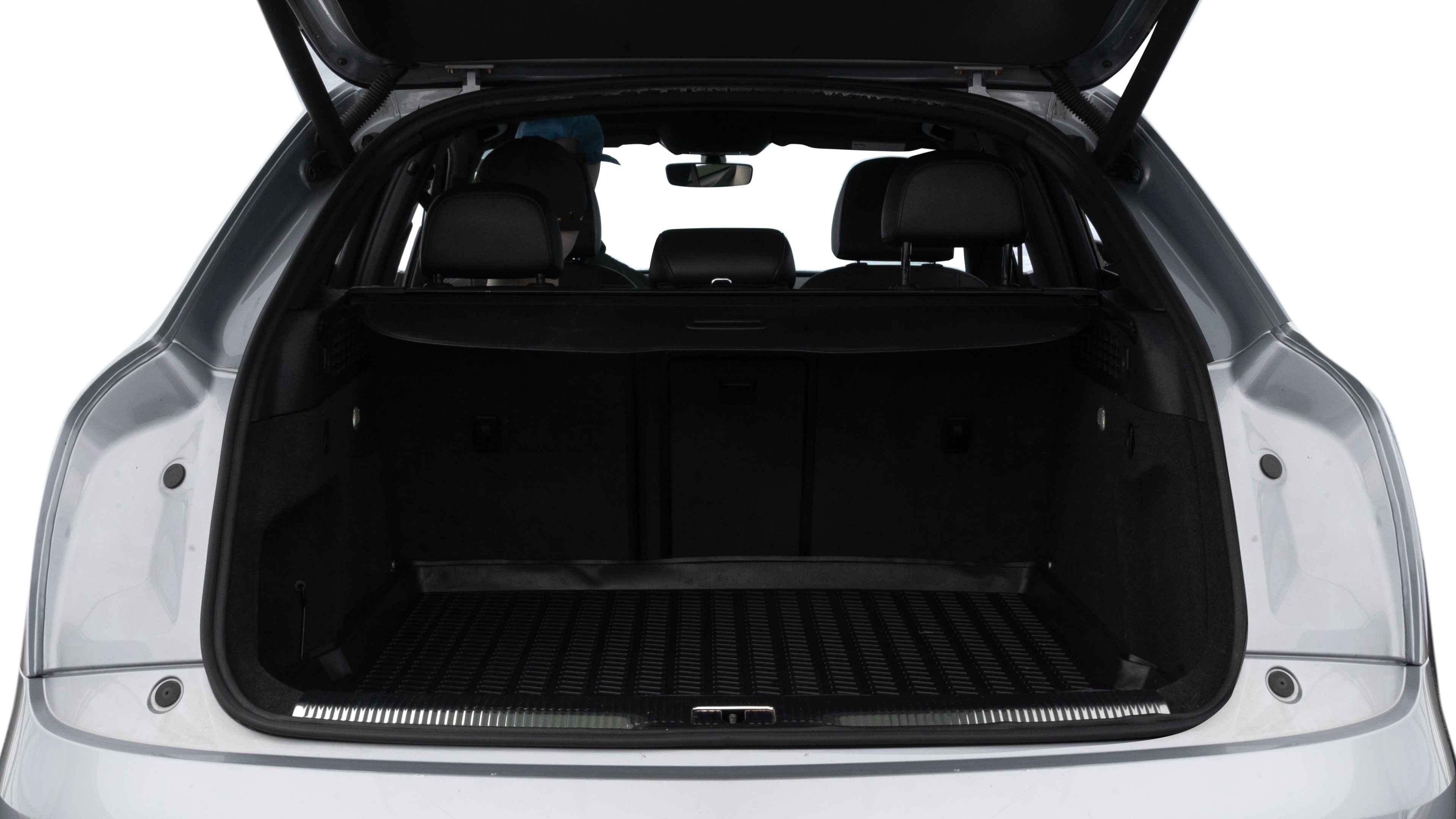 The trunk lid is open, showing full view of the trunk space. Two medium and two small suitcases are placed inside.