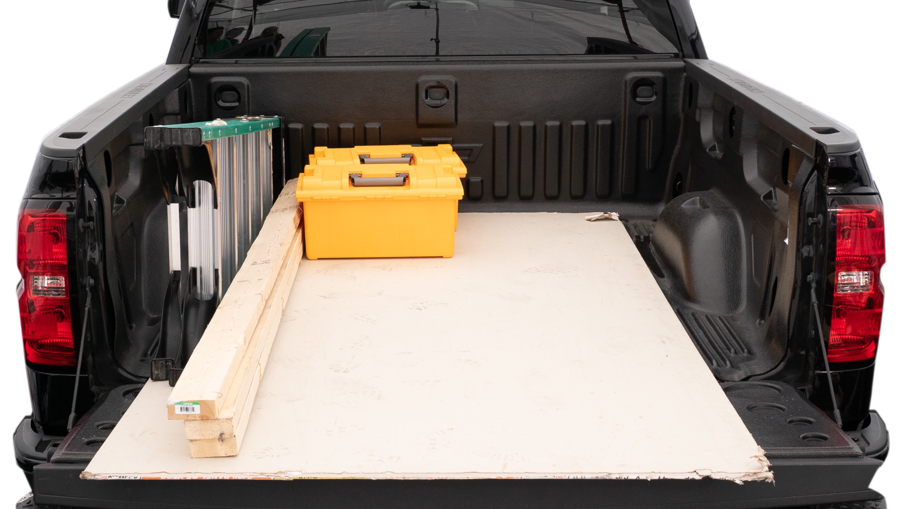 The trunk area is open giving a full view of the trunk area. A ladder, three 2 by 4 framing studs, two tool box and a 4 by 8 drywall sheet are placed inside.