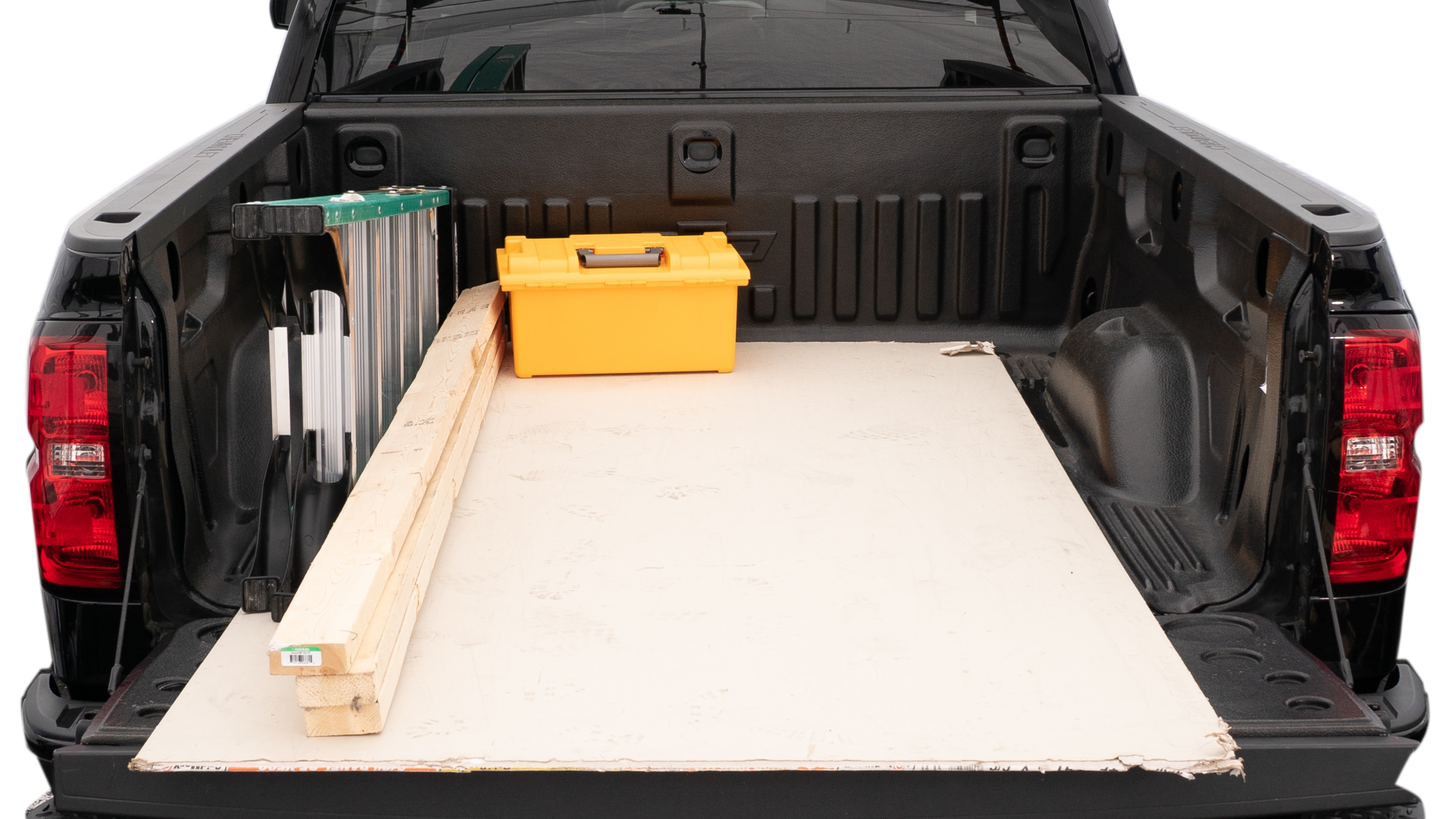 The trunk area is open giving a full view of the trunk area. A ladder, three 2 by 4 framing studs, two tool box and a 4 by 8 drywall sheet are placed inside.