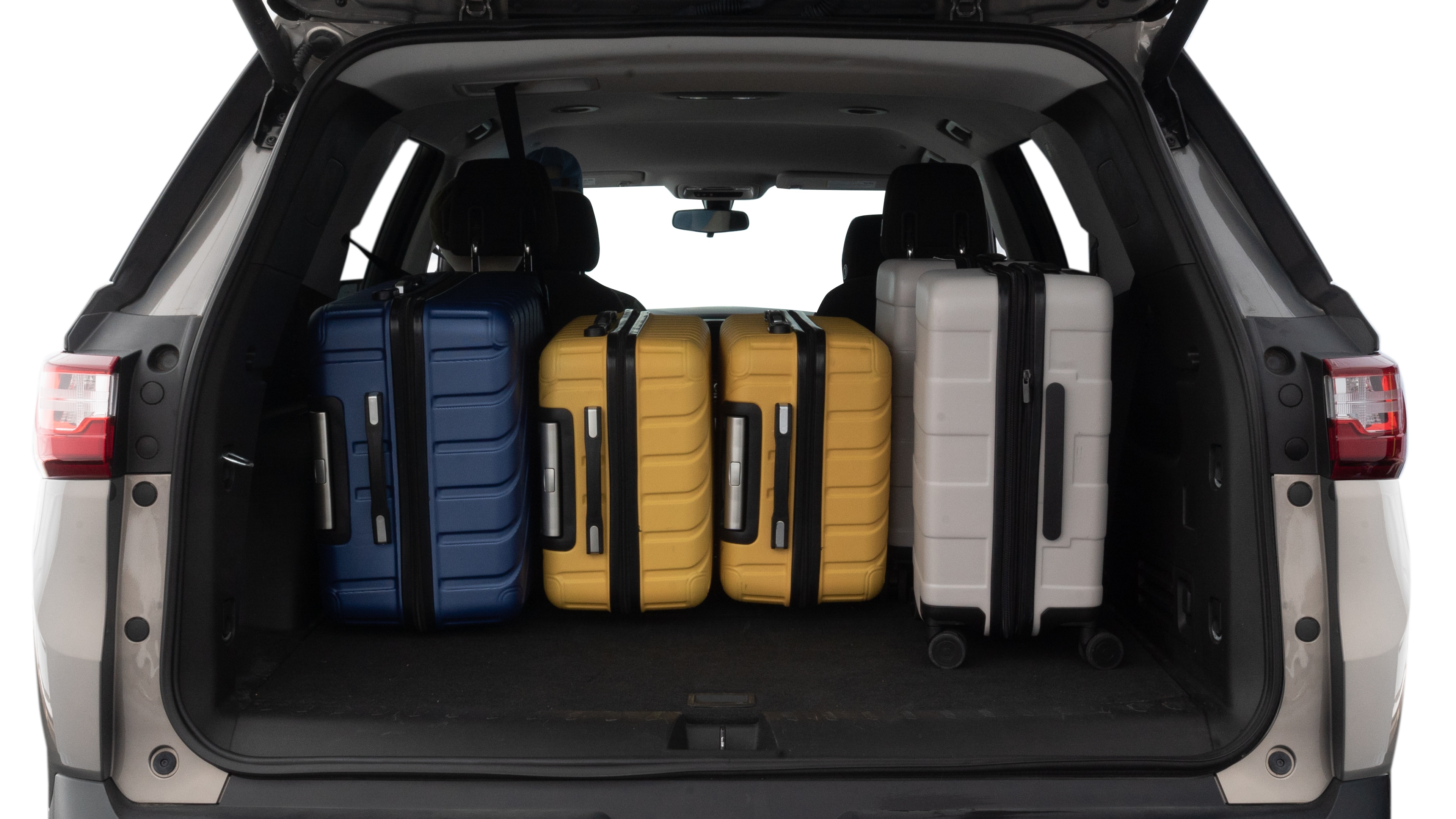 The trunk lid is open, showing full view of the trunk space. One large, two medium, and one small suitcases are placed inside.