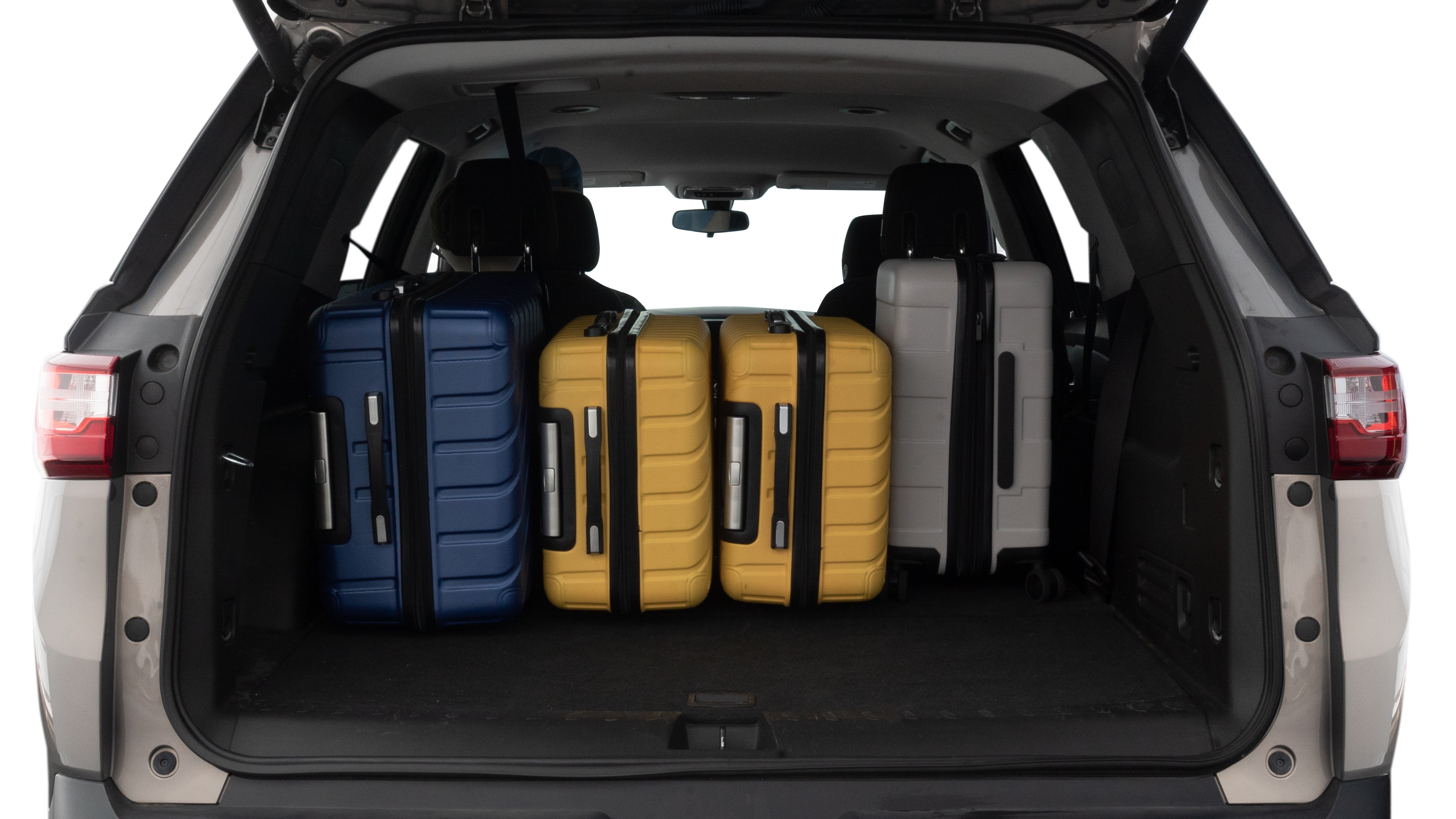 The trunk lid is open, showing full view of the trunk space. One large, two medium, and one small suitcases are placed inside.