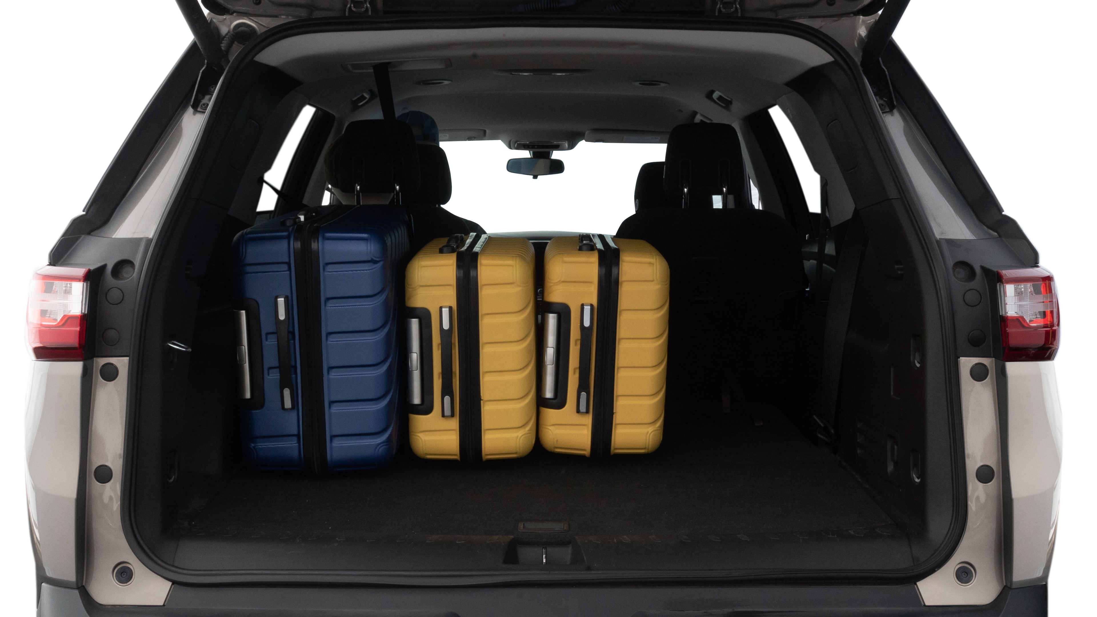 The trunk lid is open, showing full view of the trunk space. One large, two medium, and one small suitcases are placed inside.