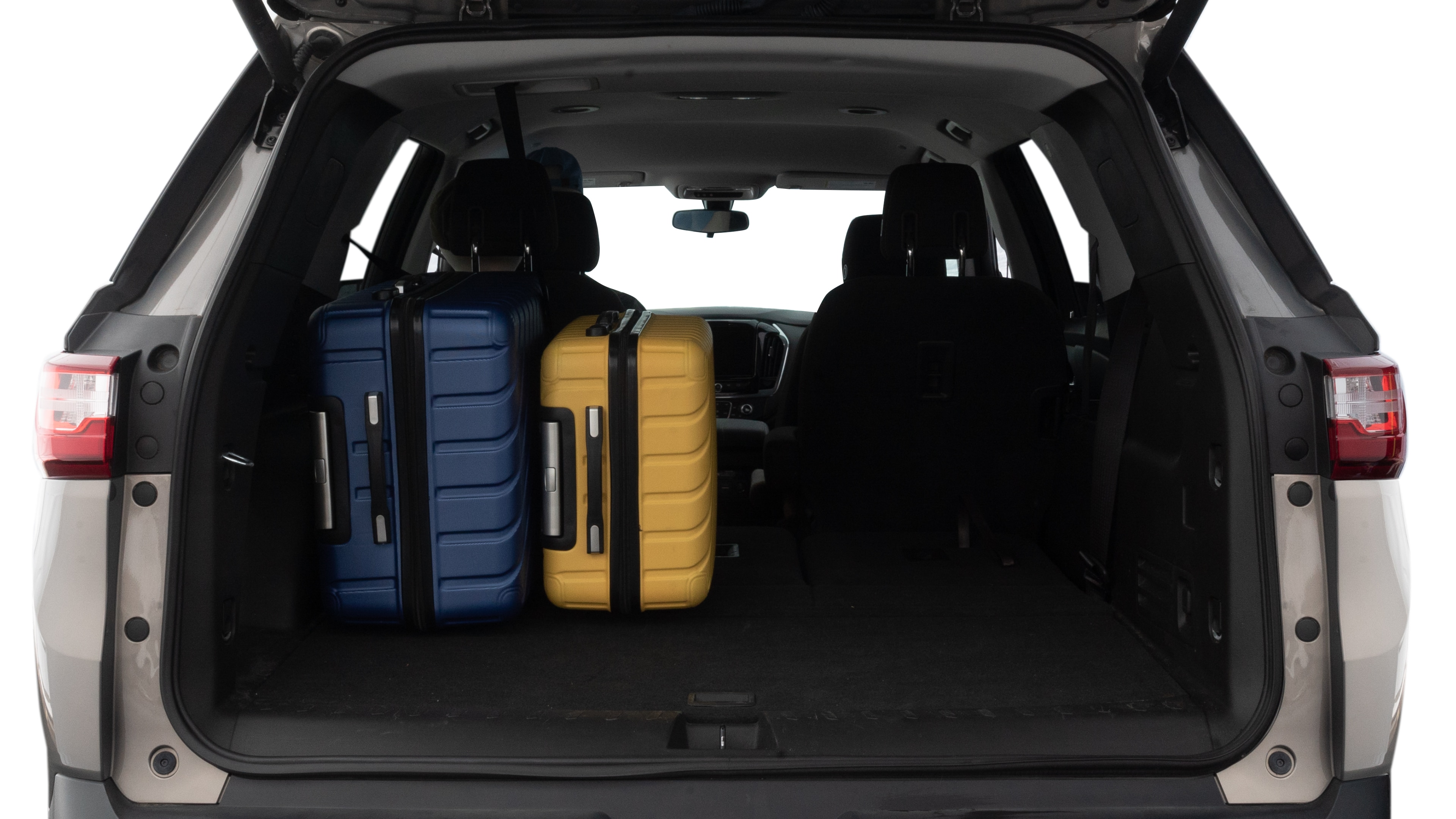 The trunk lid is open, showing full view of the trunk space. One large, two medium, and one small suitcases are placed inside.