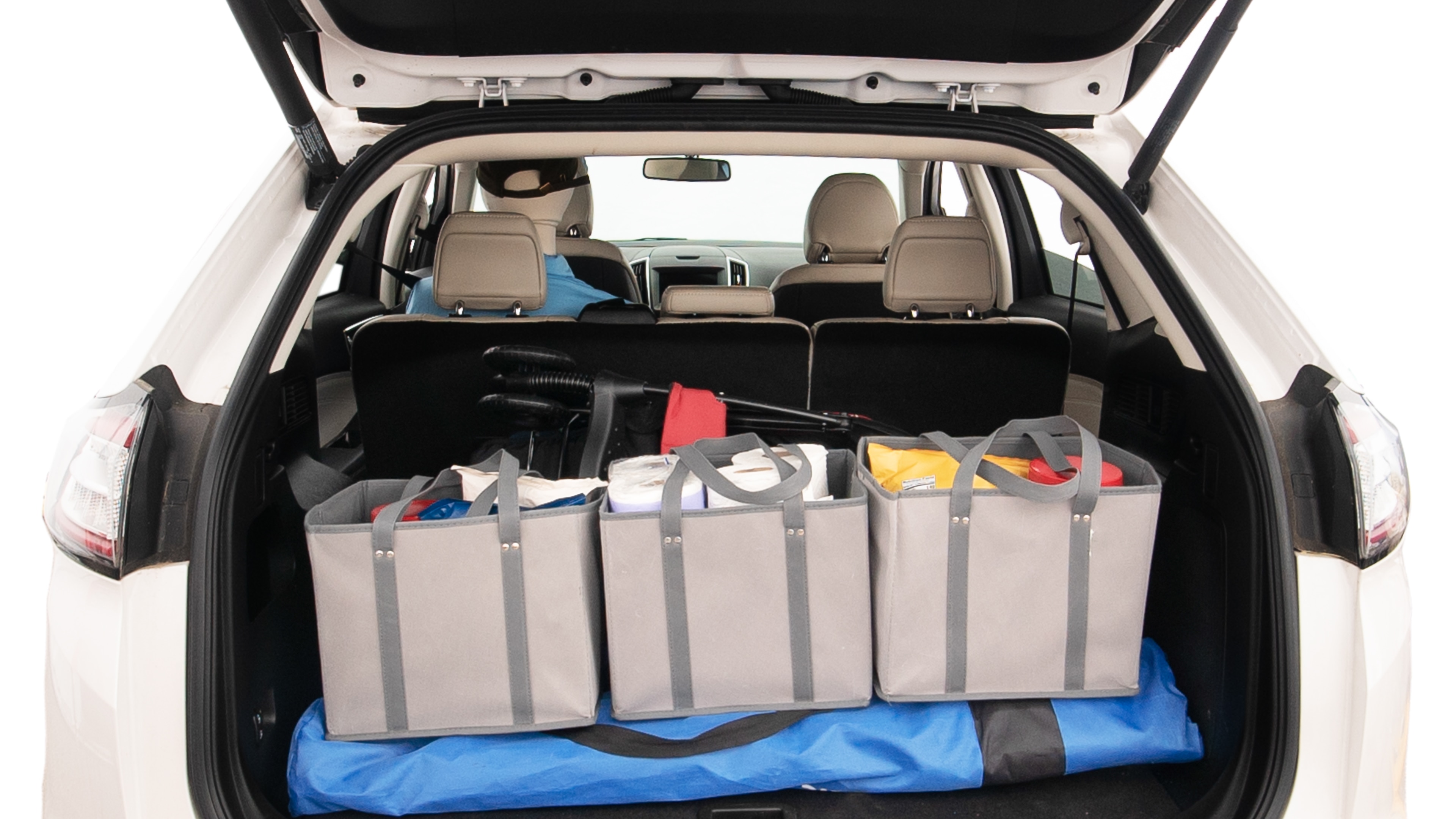 The trunk lid is open showing full view of the trunk. A baby stroller, three grocery carriers, two camping chairs in the carrying bag, and a set of golf clubs are placed inside.