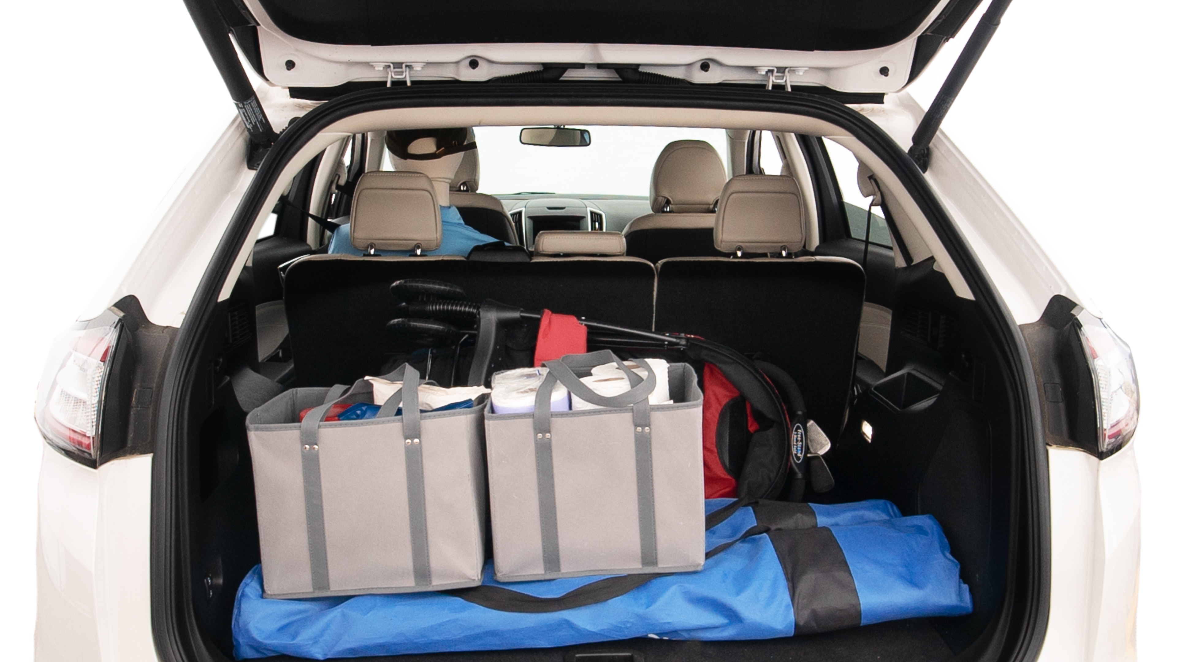 The trunk lid is open showing full view of the trunk. A baby stroller, three grocery carriers, two camping chairs in the carrying bag, and a set of golf clubs are placed inside.