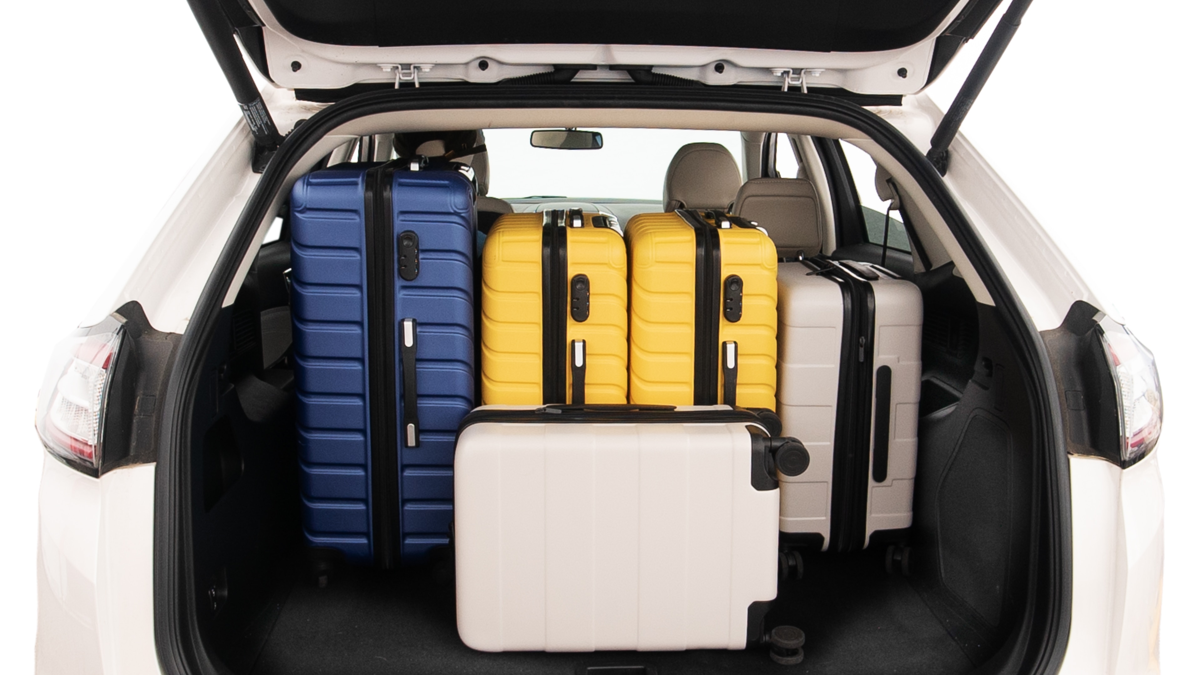 The trunk lid is open, showing full view of the trunk space. One extra large, Two large and two small suitcases are placed inside.