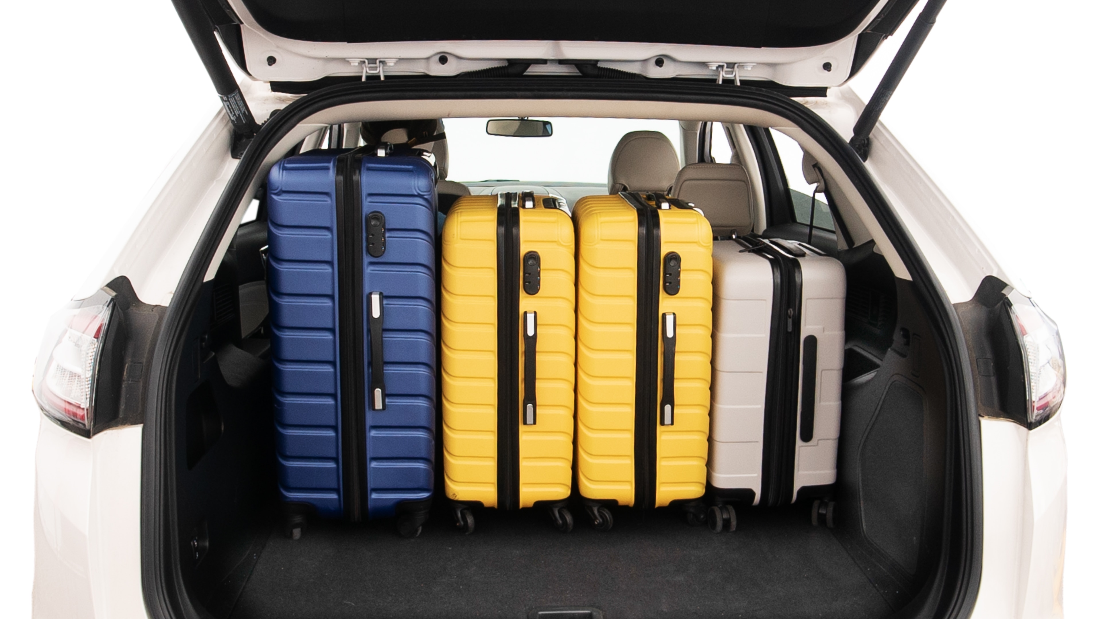 The trunk lid is open, showing full view of the trunk space. One extra large, Two large and two small suitcases are placed inside.
