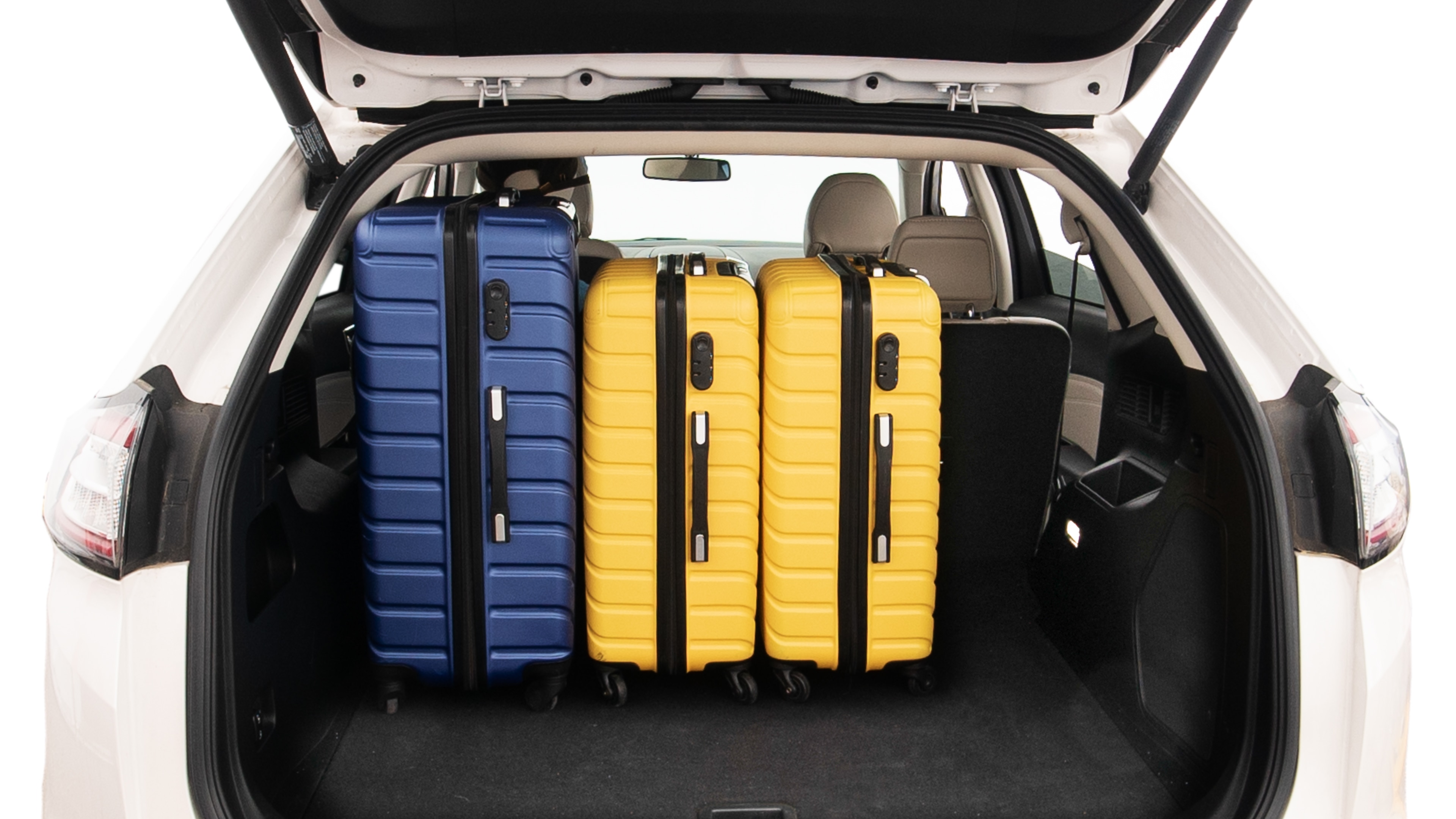 The trunk lid is open, showing full view of the trunk space. One extra large, Two large and two small suitcases are placed inside.