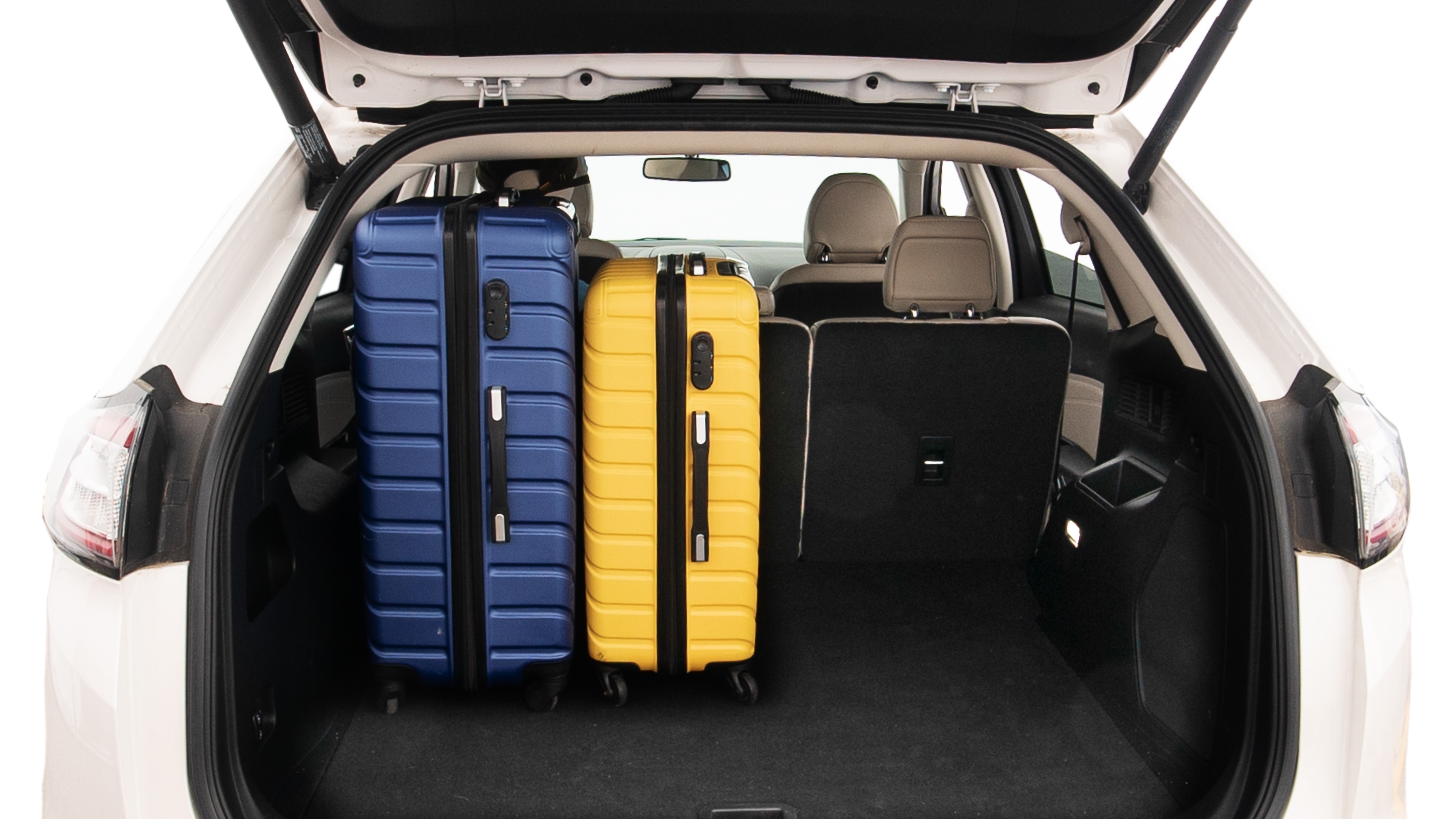 The trunk lid is open, showing full view of the trunk space. One extra large, Two large and two small suitcases are placed inside.