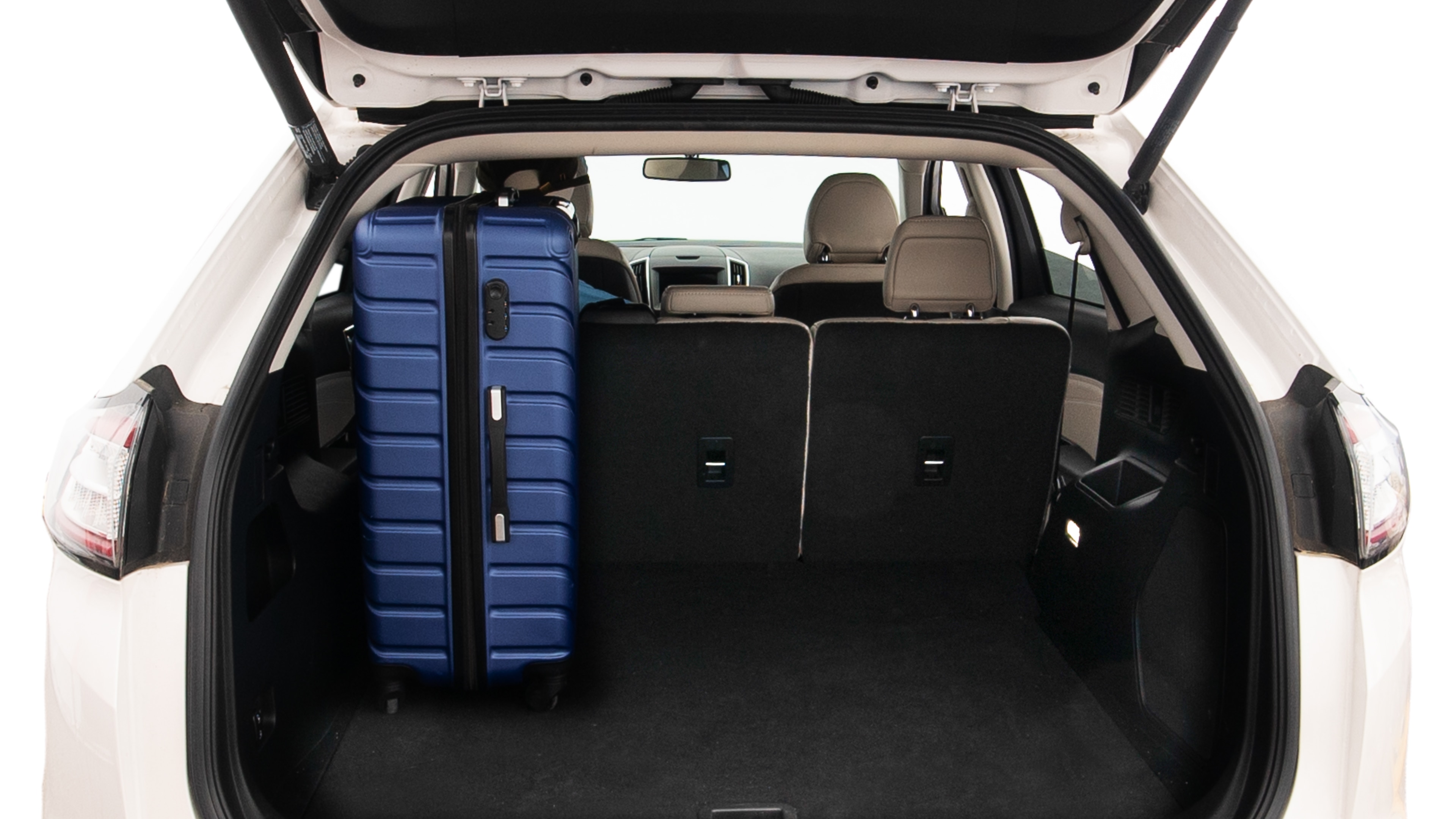 The trunk lid is open, showing full view of the trunk space. One extra large, Two large and two small suitcases are placed inside.