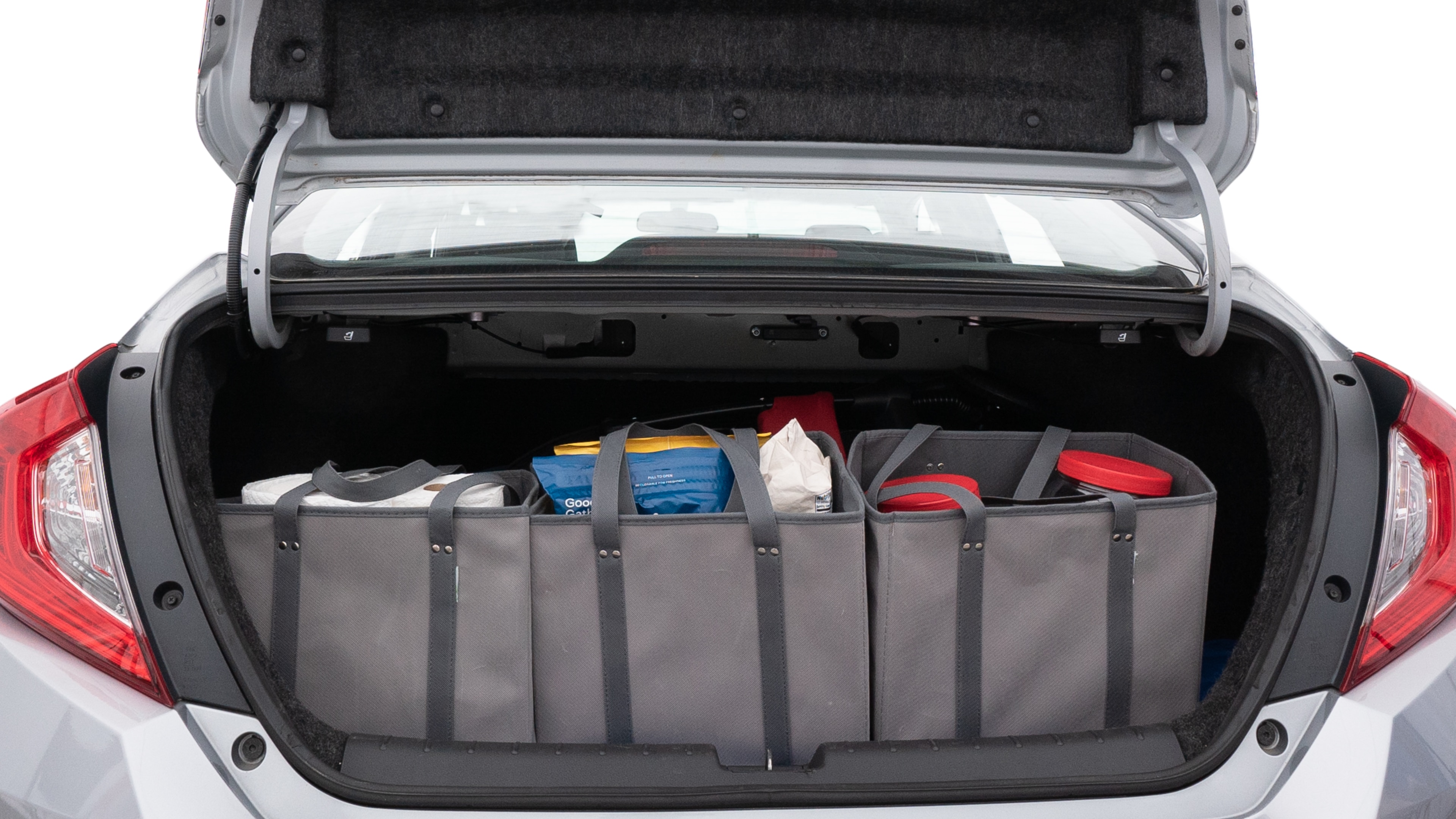 The trunk lid is open showing full view of the trunk. A baby stroller, three grocery carriers, two camping chairs in the carrying bag, and a set of golf clubs are placed inside.