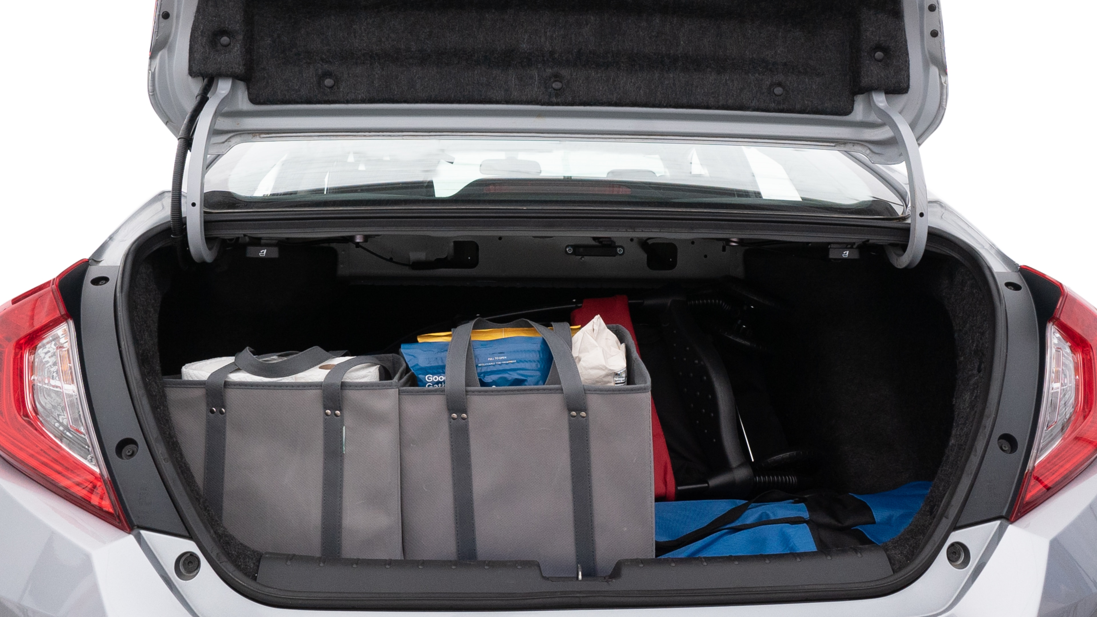 The trunk lid is open showing full view of the trunk. A baby stroller, three grocery carriers, two camping chairs in the carrying bag, and a set of golf clubs are placed inside.
