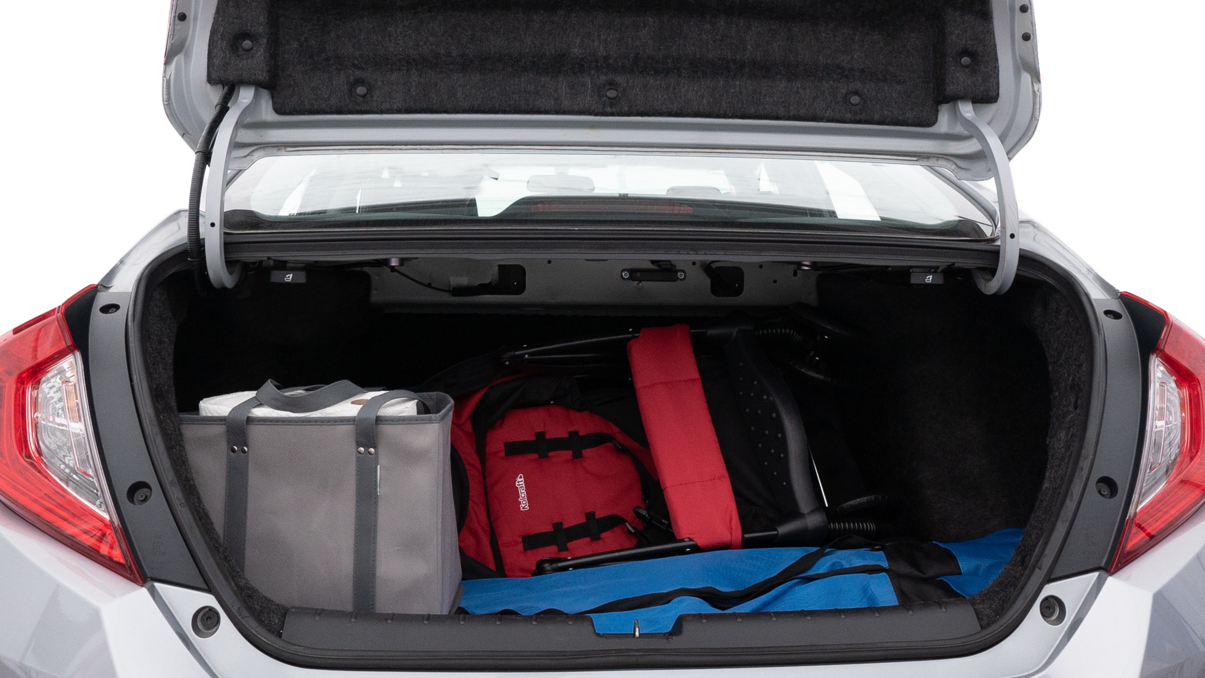 The trunk lid is open showing full view of the trunk. A baby stroller, three grocery carriers, two camping chairs in the carrying bag, and a set of golf clubs are placed inside.