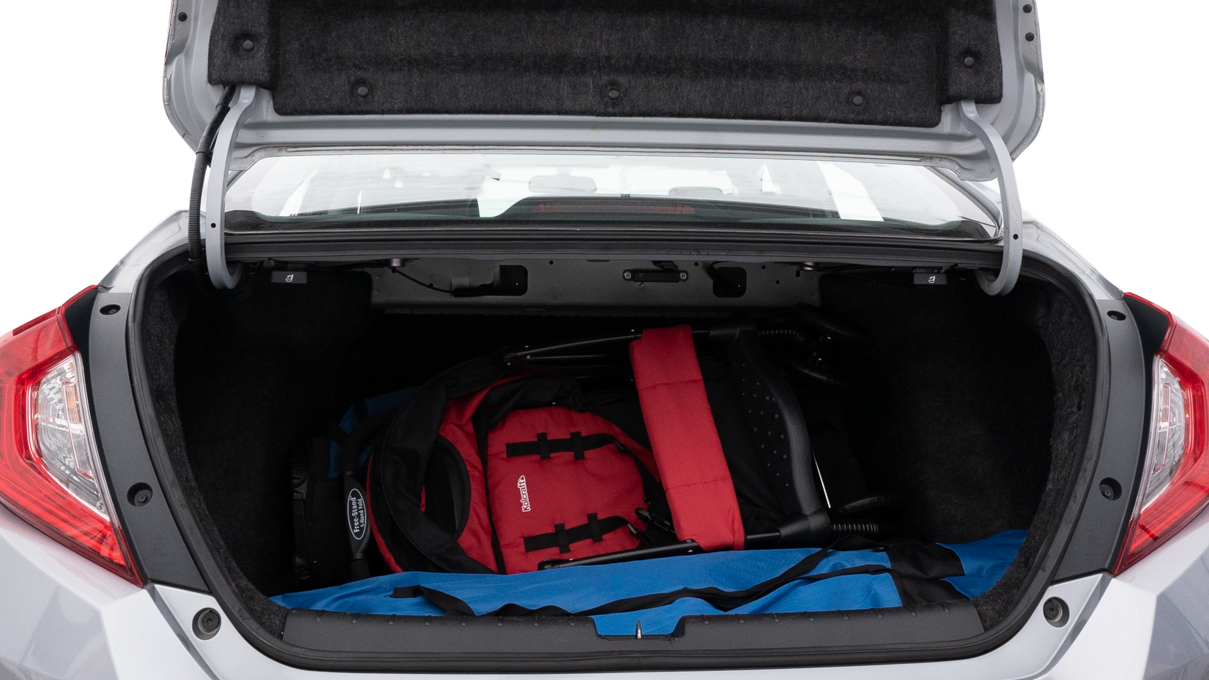 The trunk lid is open showing full view of the trunk. A baby stroller, three grocery carriers, two camping chairs in the carrying bag, and a set of golf clubs are placed inside.