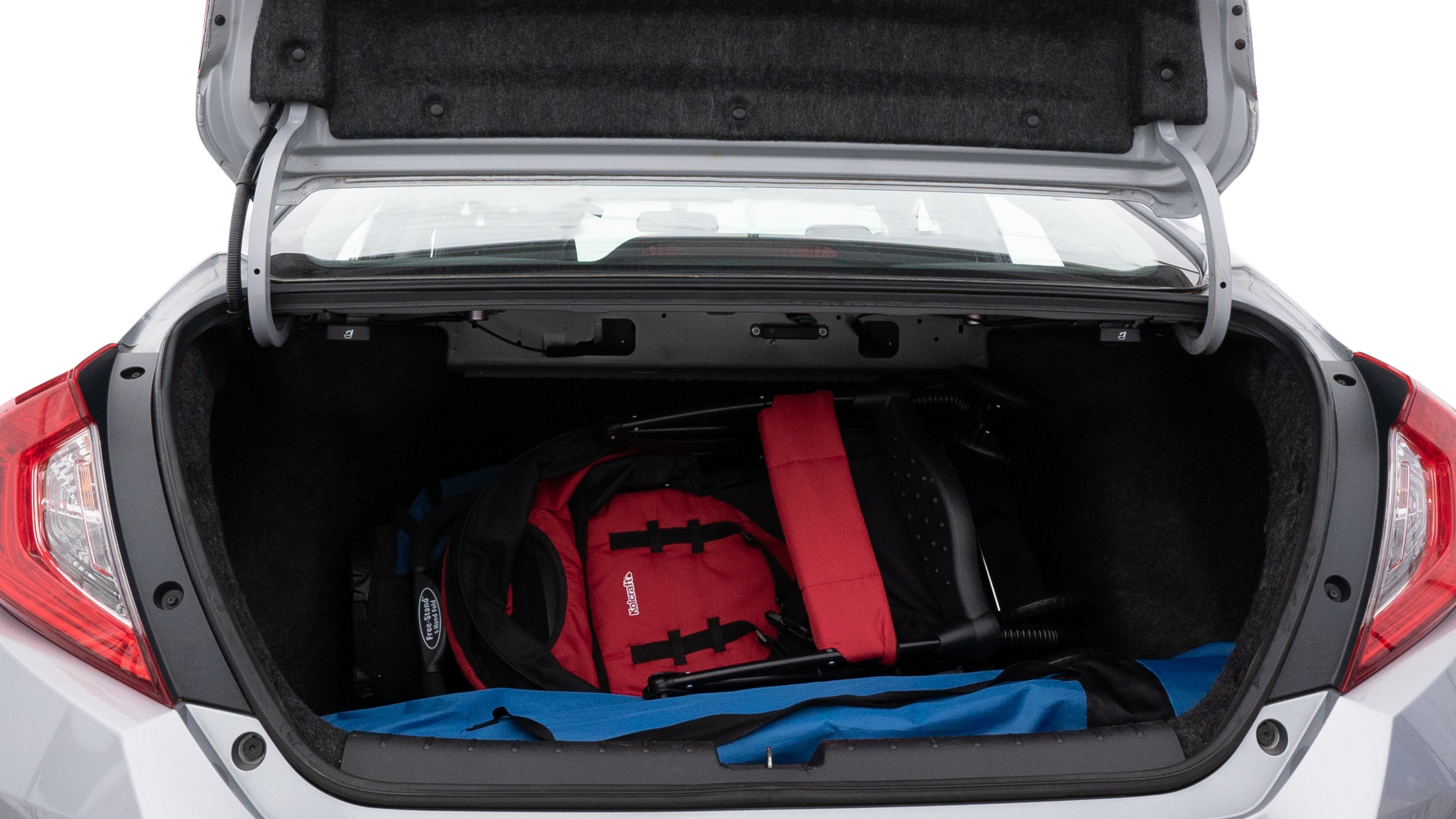 The trunk lid is open showing full view of the trunk. A baby stroller, three grocery carriers, two camping chairs in the carrying bag, and a set of golf clubs are placed inside.