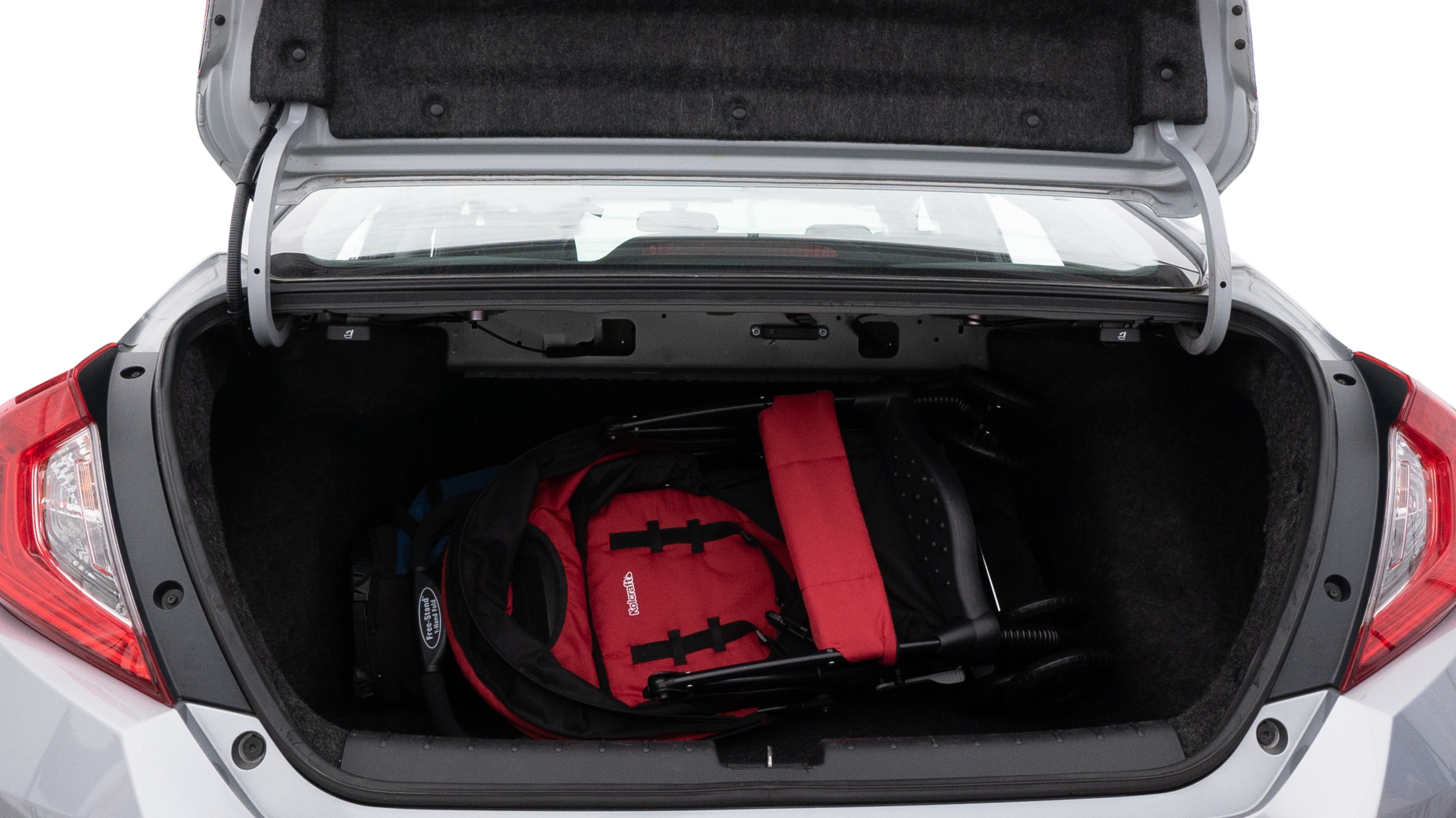 The trunk lid is open showing full view of the trunk. A baby stroller, three grocery carriers, two camping chairs in the carrying bag, and a set of golf clubs are placed inside.