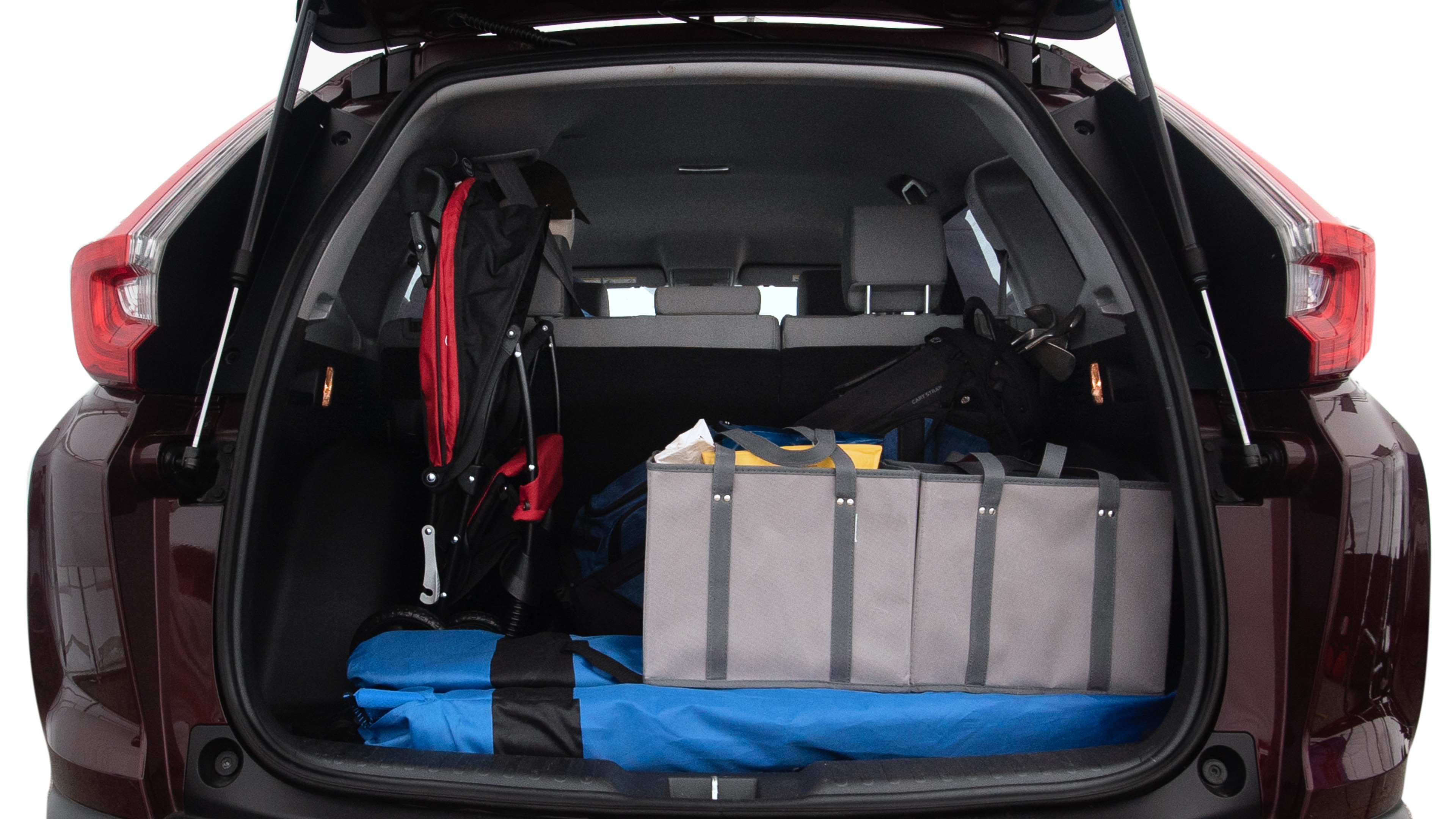 The trunk lid is open showing full view of the trunk. A baby stroller, three grocery carriers, two camping chairs in the carrying bag, and a set of golf clubs are placed inside.