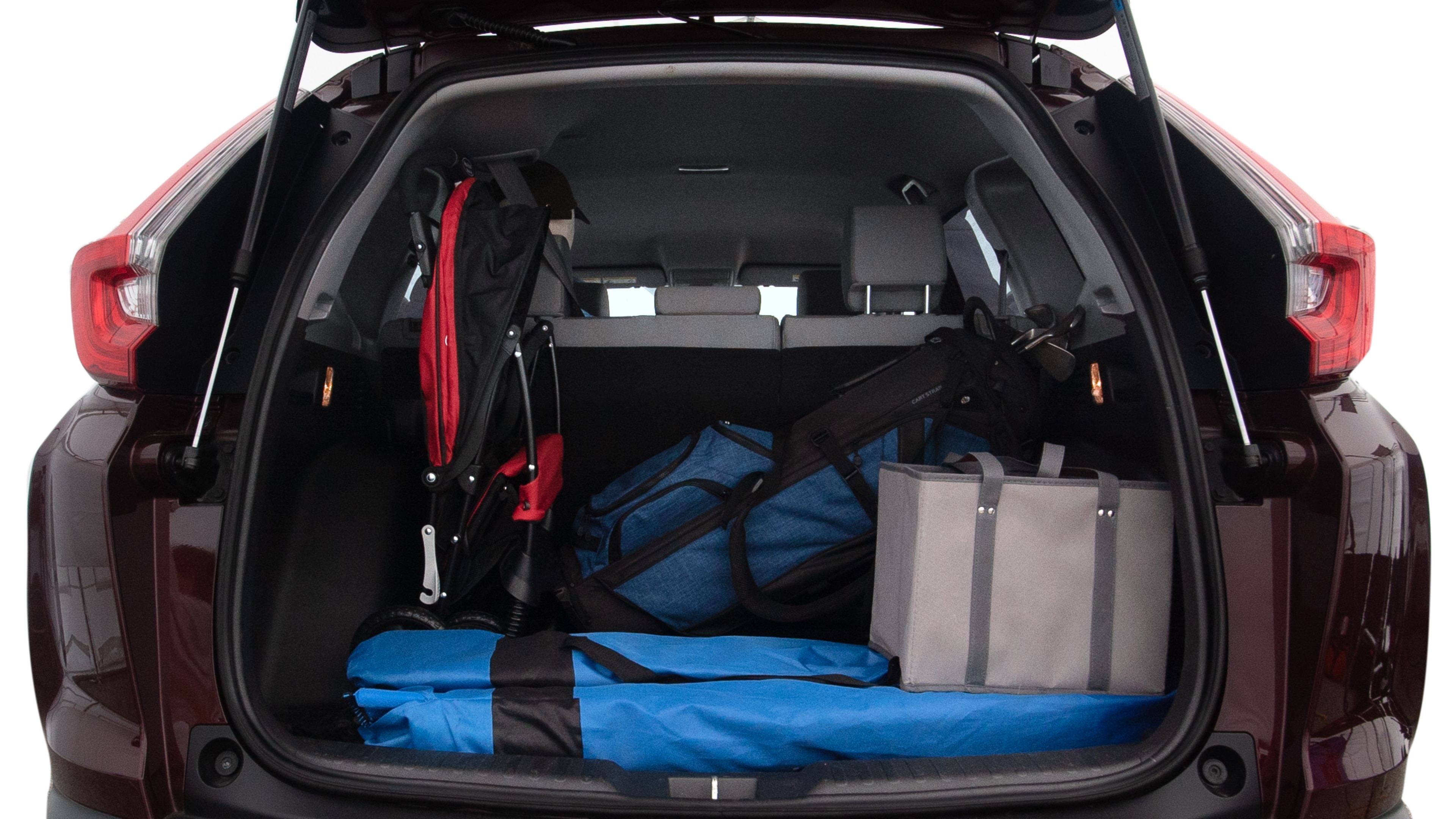 The trunk lid is open showing full view of the trunk. A baby stroller, three grocery carriers, two camping chairs in the carrying bag, and a set of golf clubs are placed inside.