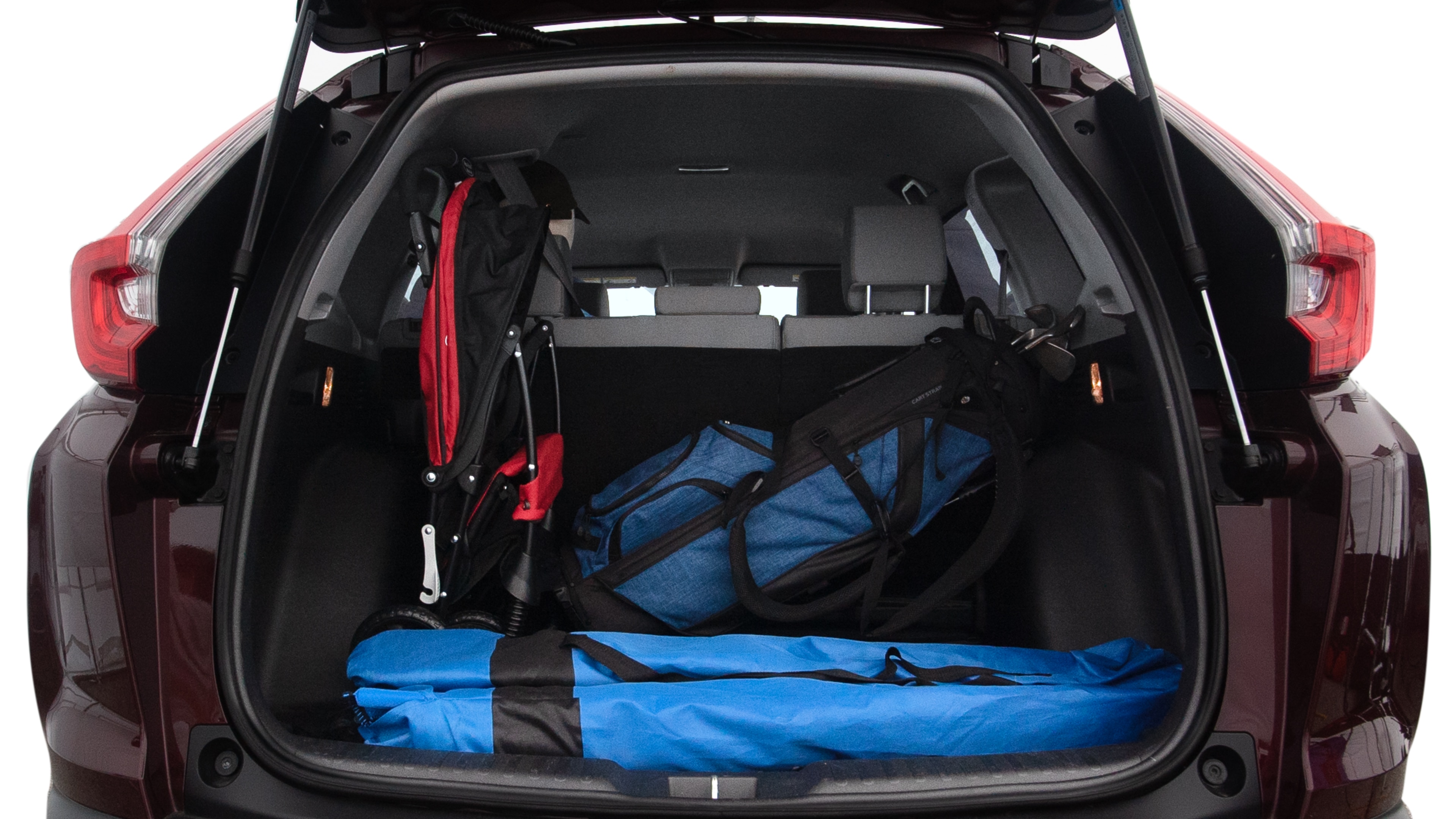 The trunk lid is open showing full view of the trunk. A baby stroller, three grocery carriers, two camping chairs in the carrying bag, and a set of golf clubs are placed inside.