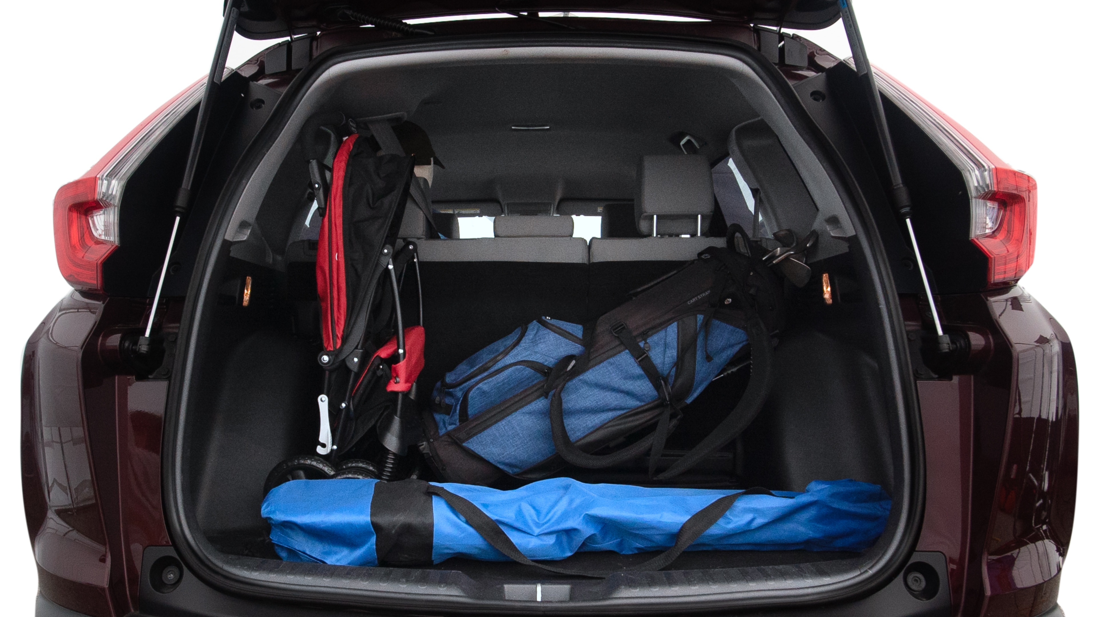 The trunk lid is open showing full view of the trunk. A baby stroller, three grocery carriers, two camping chairs in the carrying bag, and a set of golf clubs are placed inside.