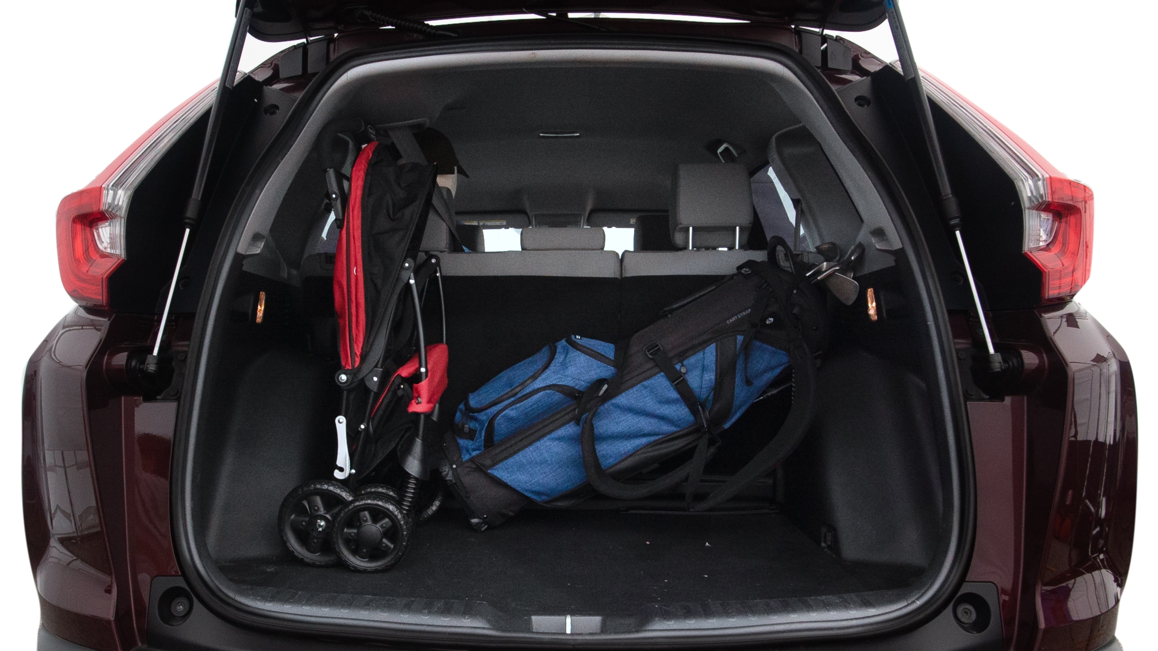 The trunk lid is open showing full view of the trunk. A baby stroller, three grocery carriers, two camping chairs in the carrying bag, and a set of golf clubs are placed inside.