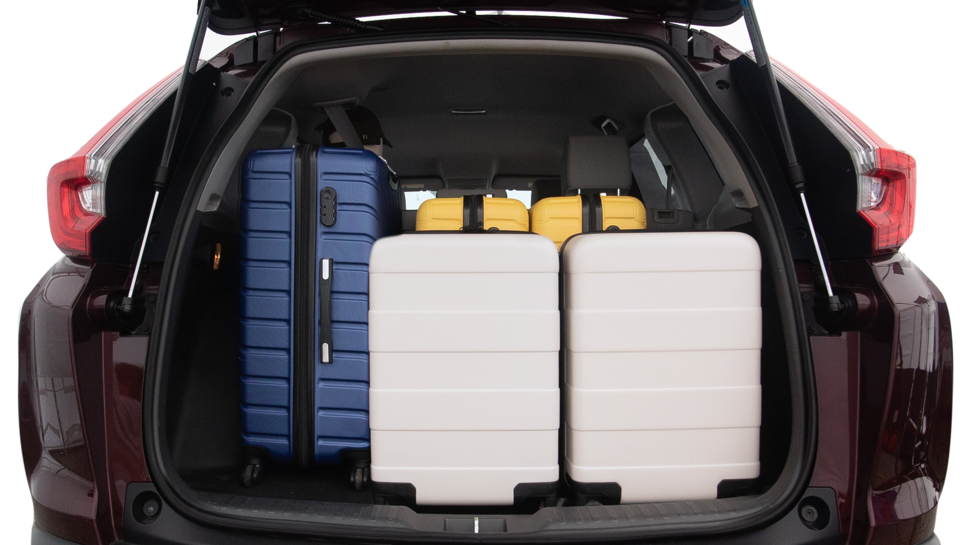 The trunk lid is open, showing full view of the trunk space. One large, two medium, and two small suitcases are placed inside.