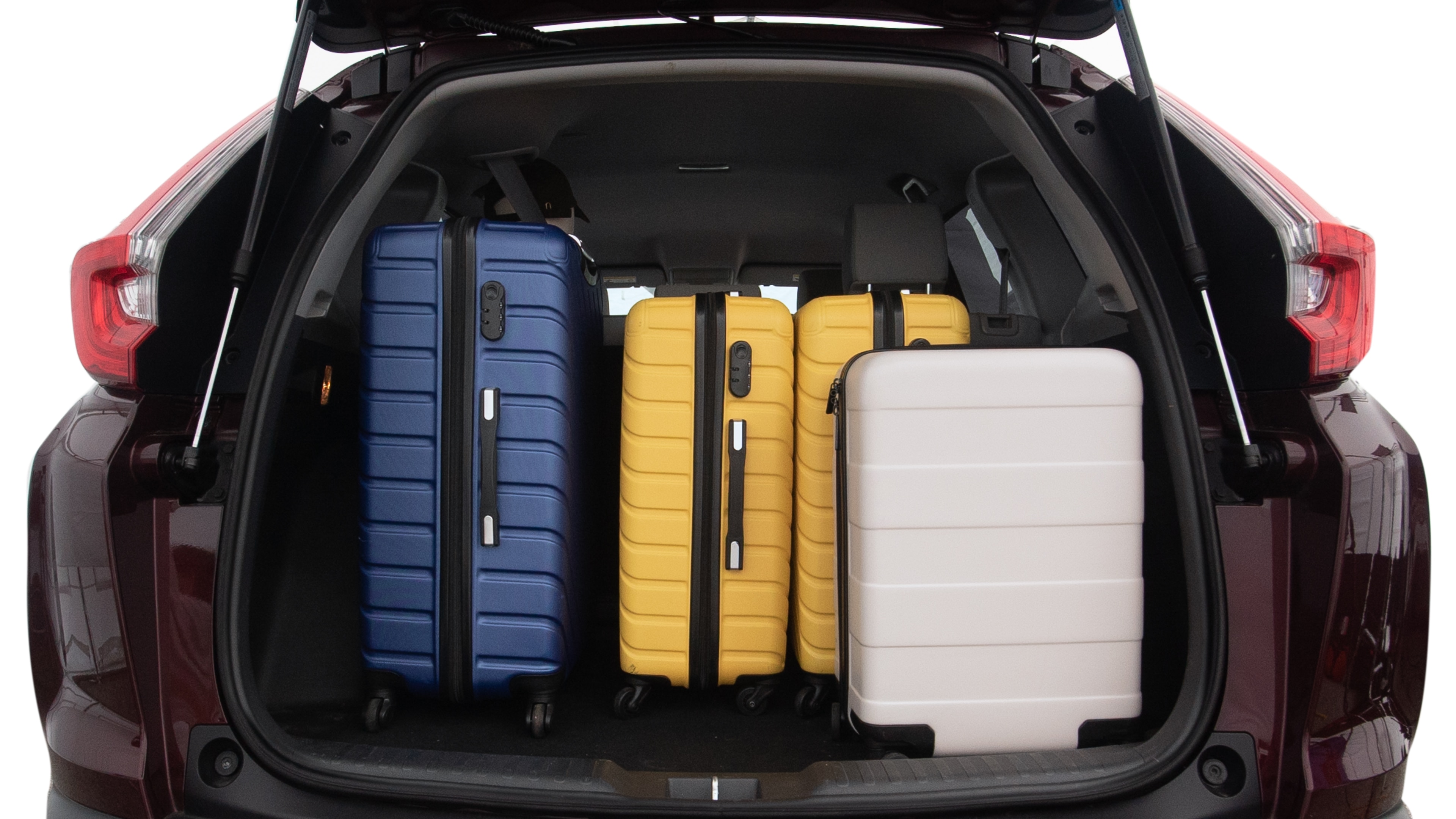 The trunk lid is open, showing full view of the trunk space. One large, two medium, and two small suitcases are placed inside.