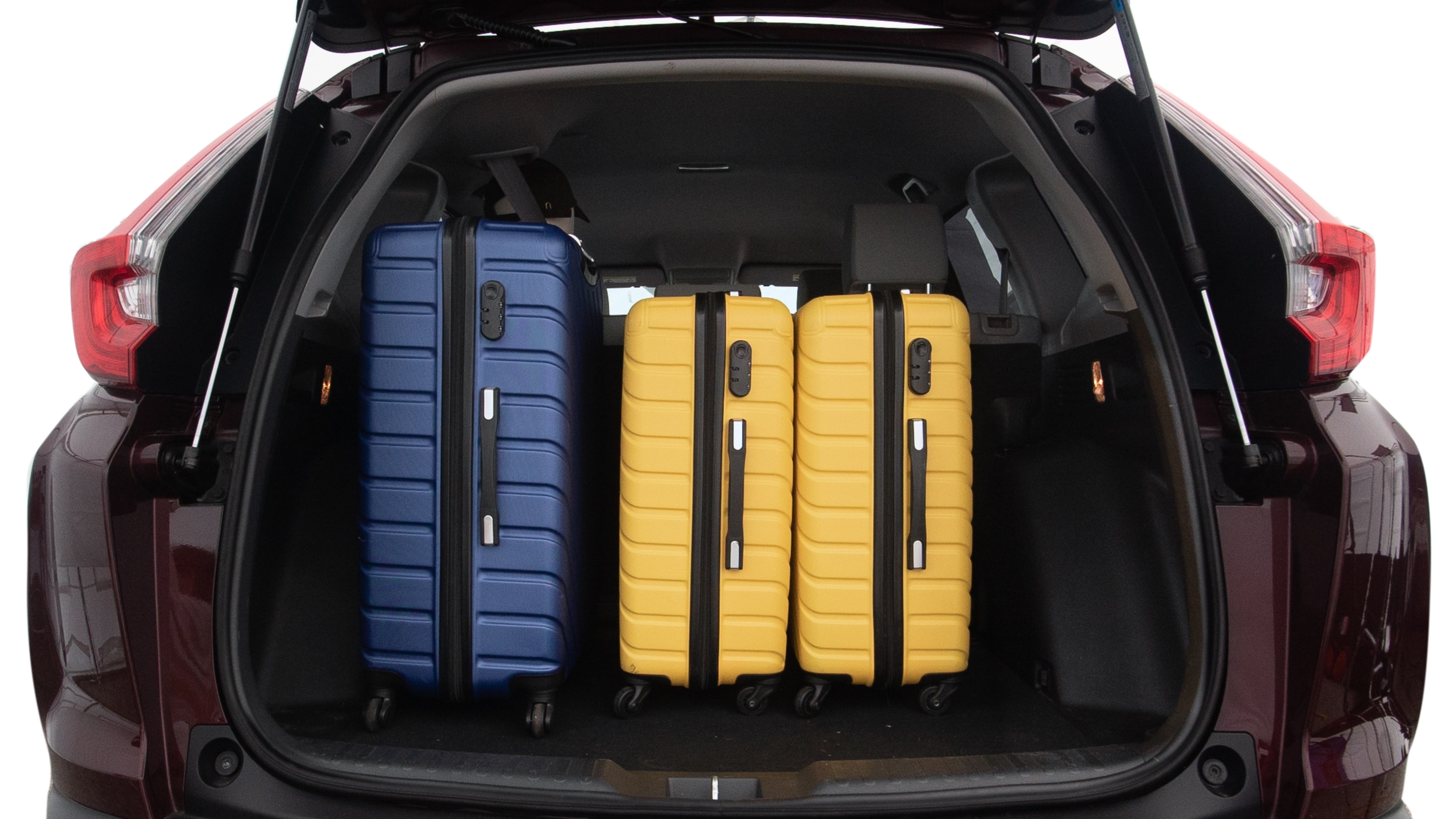 The trunk lid is open, showing full view of the trunk space. One large, two medium, and two small suitcases are placed inside.