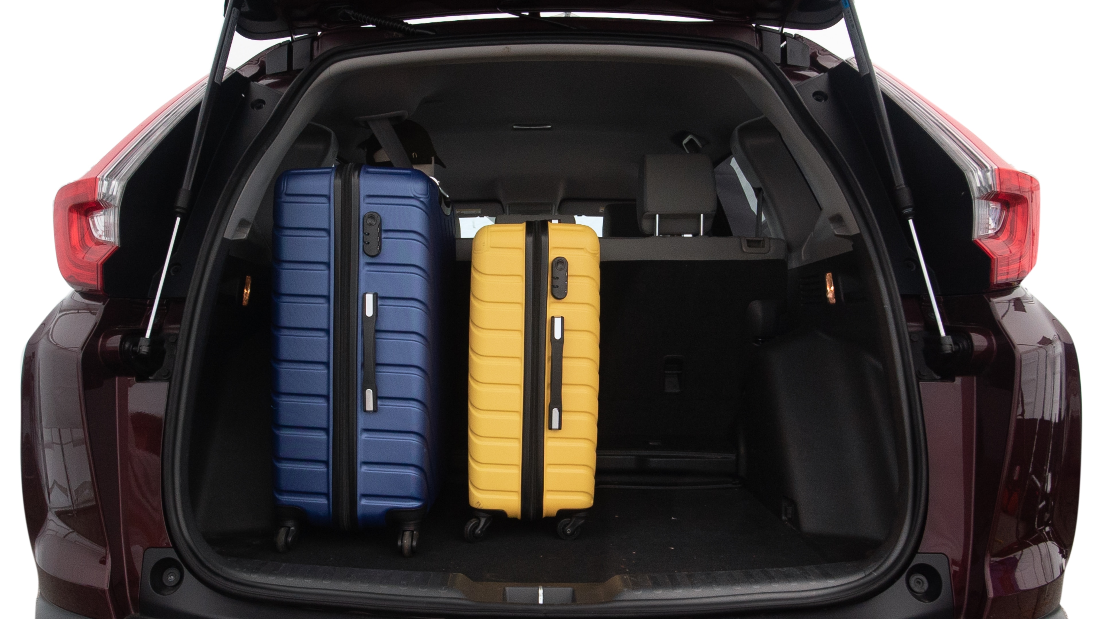 The trunk lid is open, showing full view of the trunk space. One large, two medium, and two small suitcases are placed inside.