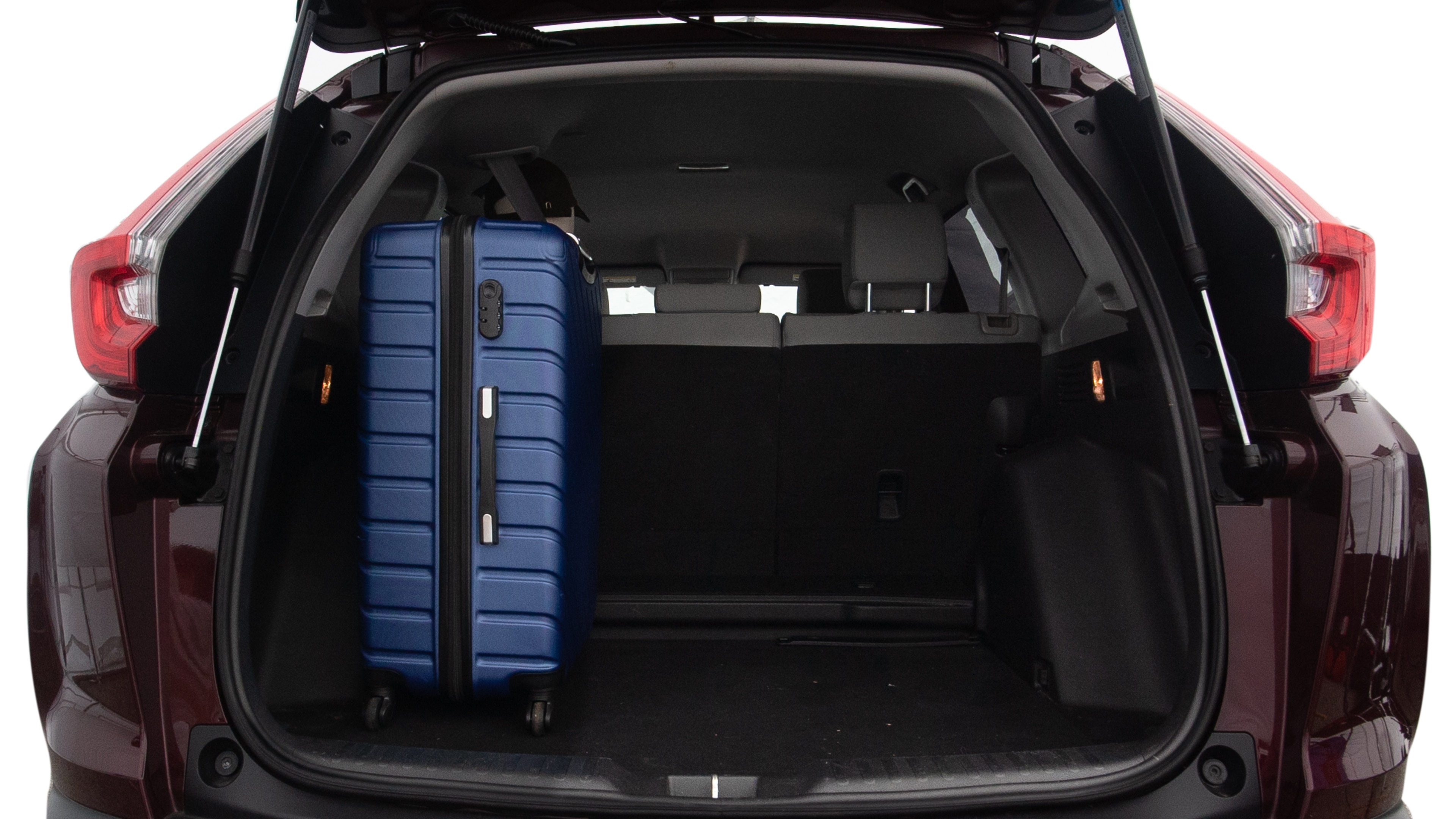The trunk lid is open, showing full view of the trunk space. One large, two medium, and two small suitcases are placed inside.
