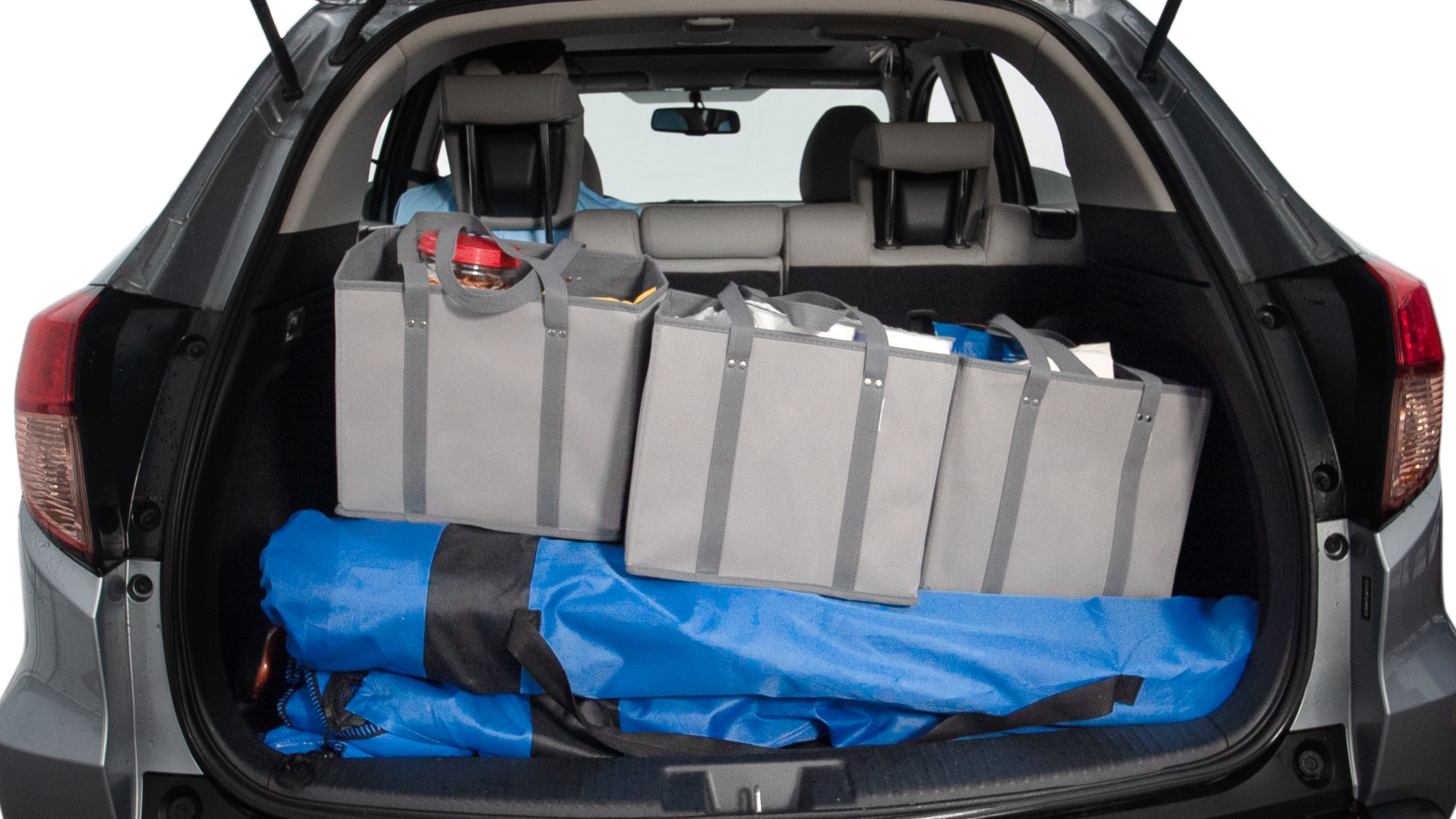 The trunk lid is open showing full view of the trunk. A baby stroller, three grocery carriers, two camping chairs in the carrying bag, and a set of golf clubs are placed inside.