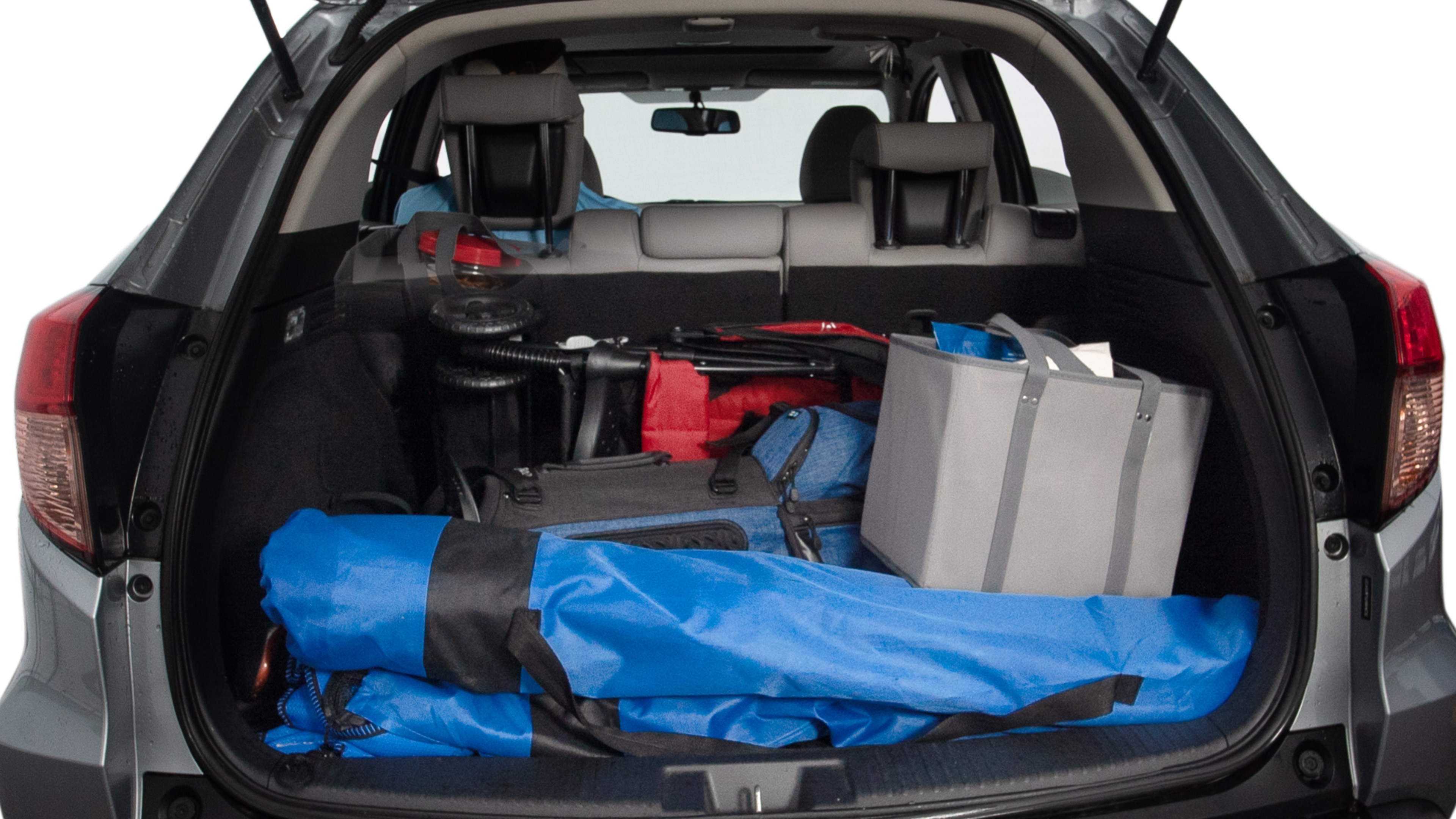 The trunk lid is open showing full view of the trunk. A baby stroller, three grocery carriers, two camping chairs in the carrying bag, and a set of golf clubs are placed inside.